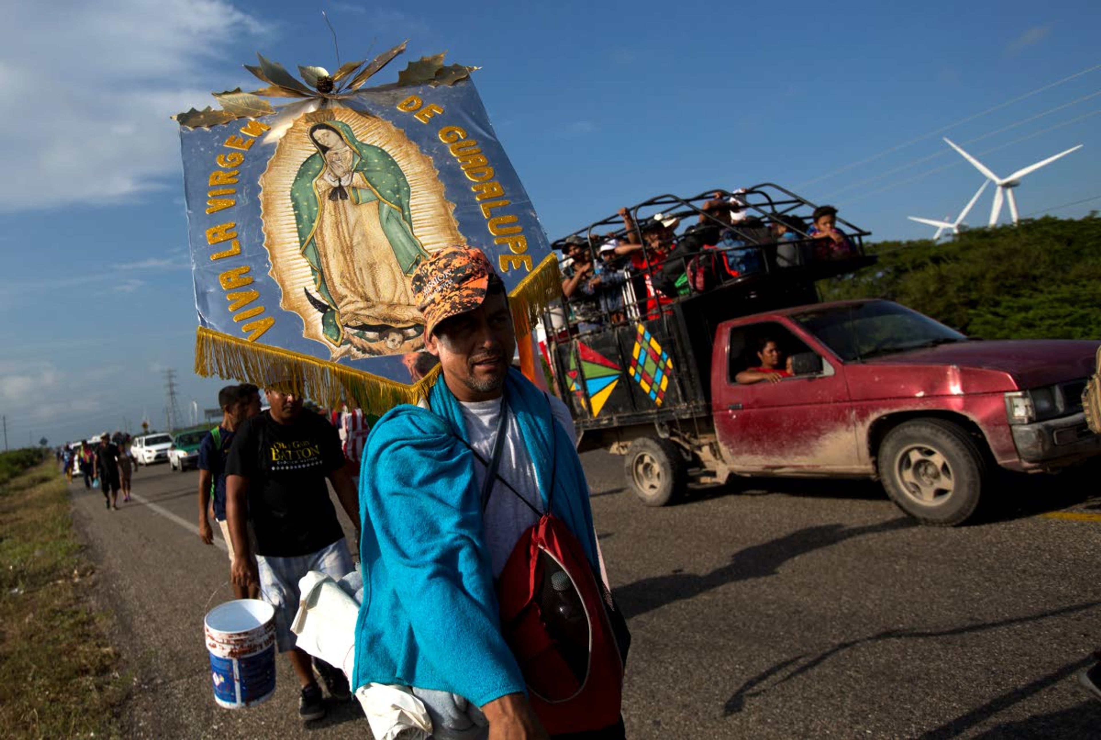 Erlin Troches, a 43-year-old Honduran migrant from the city of Santa Barbara, carries an image of the Virgin of Guadalupe that was given to him by a priest in southern Mexico, as he walks along with a thousands-strong caravan of Central Americans hoping to reach the U.S. border moves, outside Juchitan, Oaxaca state, Mexico, Thursday, Nov. 1, 2018. Troches plans to carry the religious icon with him on the entire journey, saying she symbolizes "trust, faith, and hope" that he will make it to the U.S. border. (AP Photo/Rebecca Blackwell)