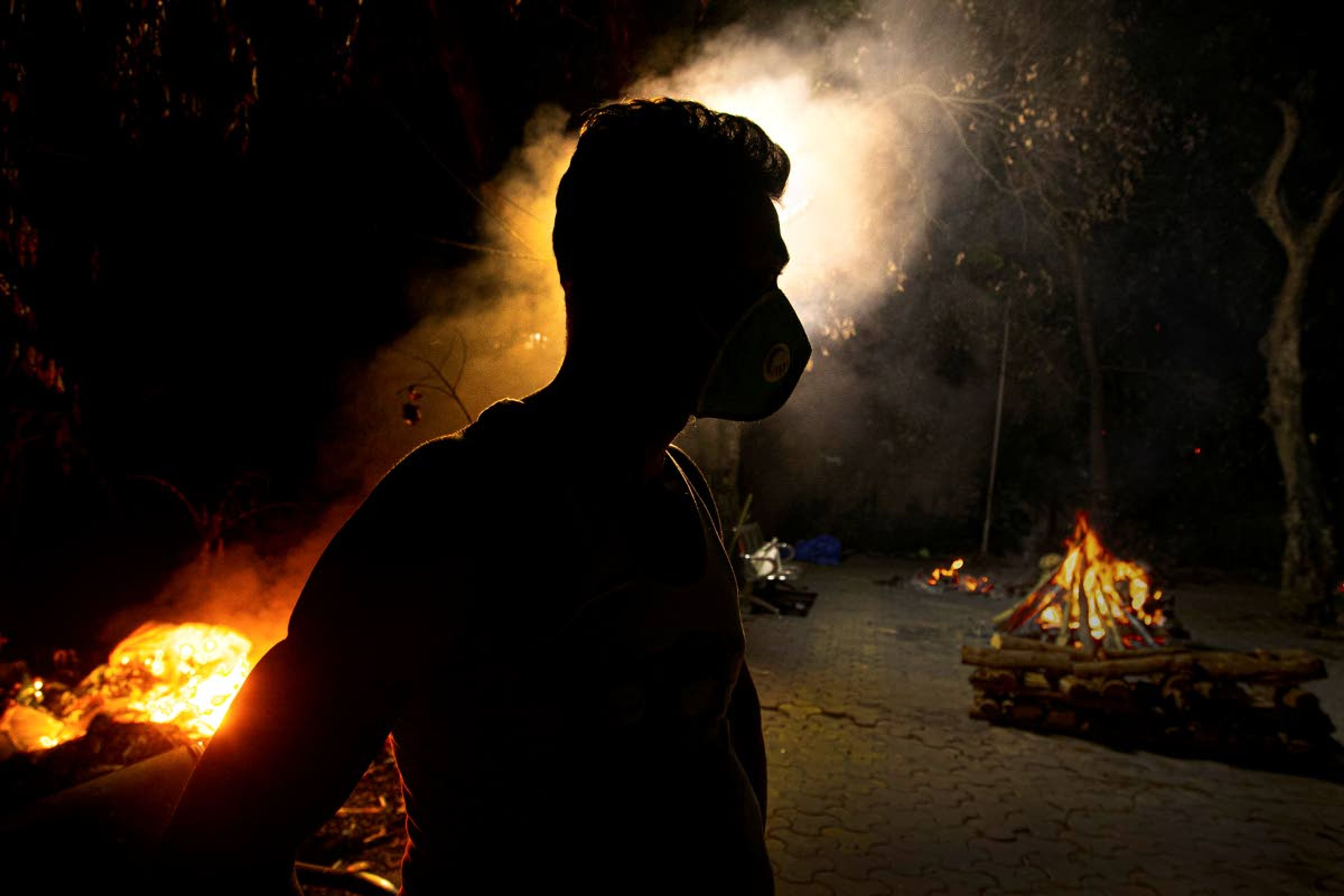 Ramananda Sarkar, 43, stands by burning funeral pyres of COVID-19 victims in Gauhati, India, Monday, Sept. 14, 2020. Sarkar, who was deep in debt and desperate for money, took the job of lighting funeral pyres after failing to pay back a loan he'd taken to start selling sugarcane juice on a wooden cart. While Hindu's believe cremation rights are sacred and release the dead person's soul from the cycle of rebirth, those who actually deal with corpses are looked down upon. Sarkar said he alone has cremated more than 450 COVID-19 victims. (AP Photo/Anupam Nath)