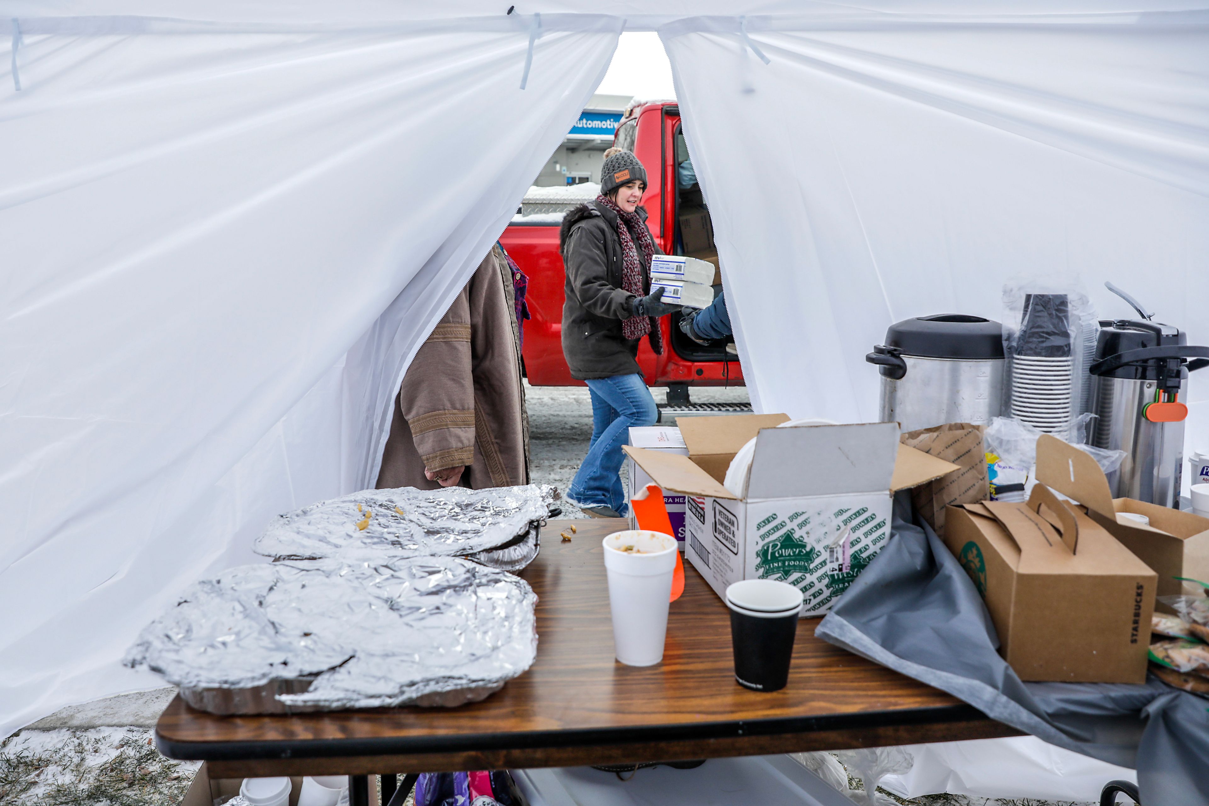 Amanda Cox, with Elves for the homeless, accepts donations from people for the homeless camp behind Walmart at a warming tent outside the Chef Store Sunday in Clarkston.