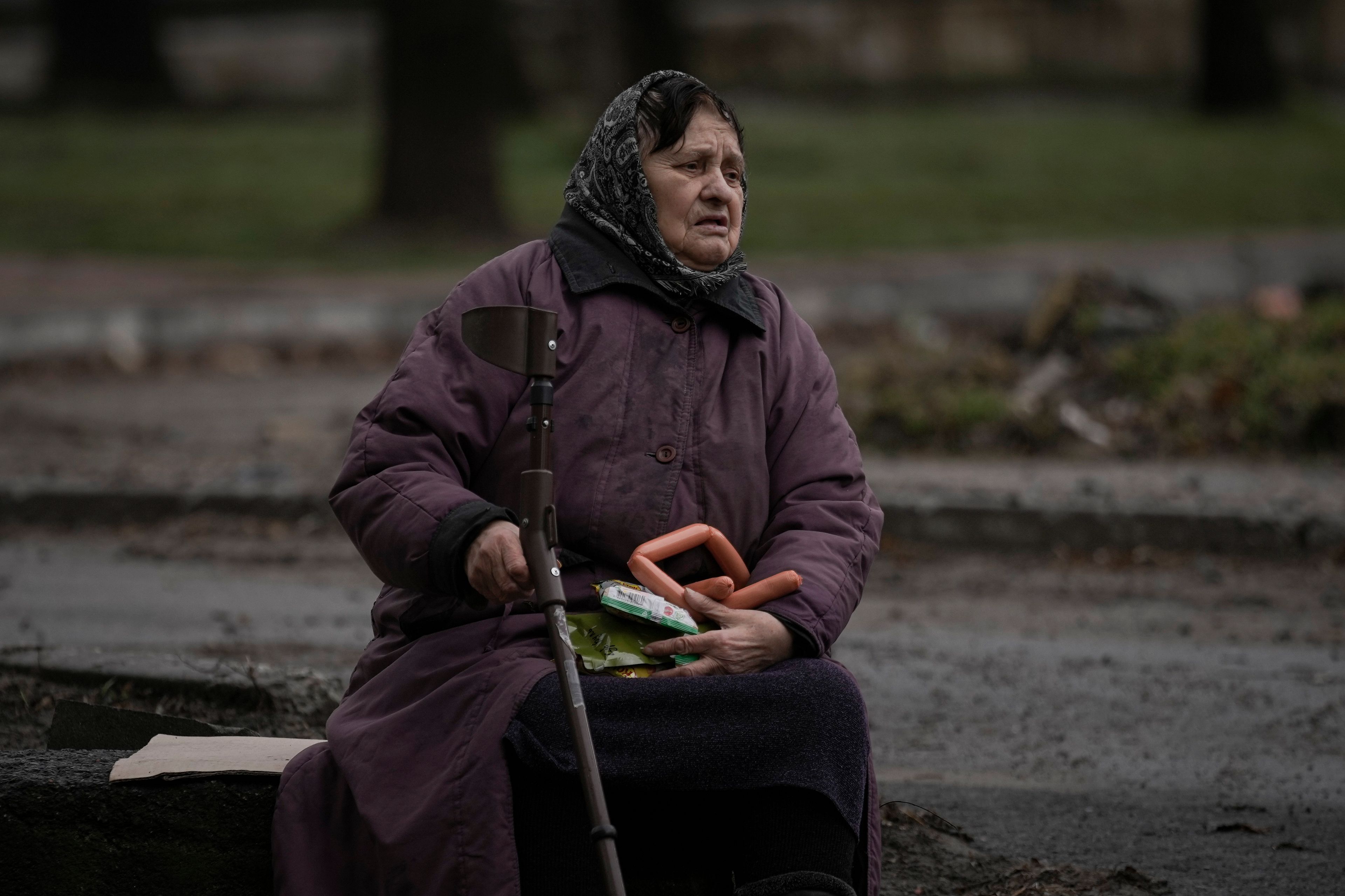 A woman holds food items she received after a convoy of military and aid vehicles arrived in the formerly Russian-occupied Kyiv suburb of Bucha, Ukraine, Saturday, April 2, 2022. As Russian forces pull back from Ukraine's capital region, retreating troops are creating a "catastrophic" situation for civilians by leaving mines around homes, abandoned equipment and "even the bodies of those killed," President Volodymyr Zelenskyy warned Saturday.(AP Photo/Vadim Ghirda)