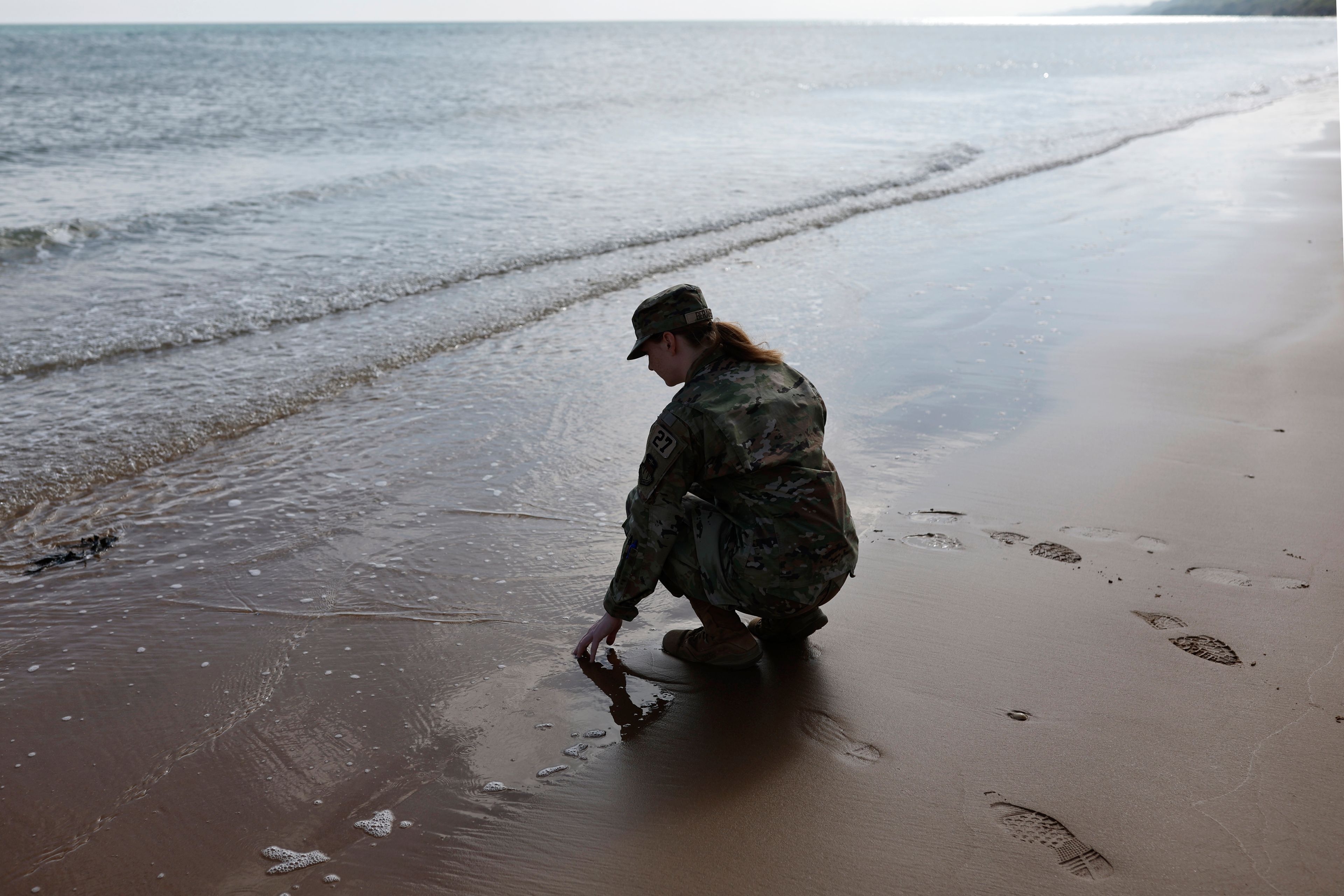 An American soldier touches the sand on Omaha Beach, Tuesday, June 4, 2024 in Normandy. World War II veterans from across the United States as well as Britain and Canada are in Normandy this week to mark 80 years since the D-Day landings that helped lead to Hitler's defeat. (AP Photo/Jeremias Gonzalez)