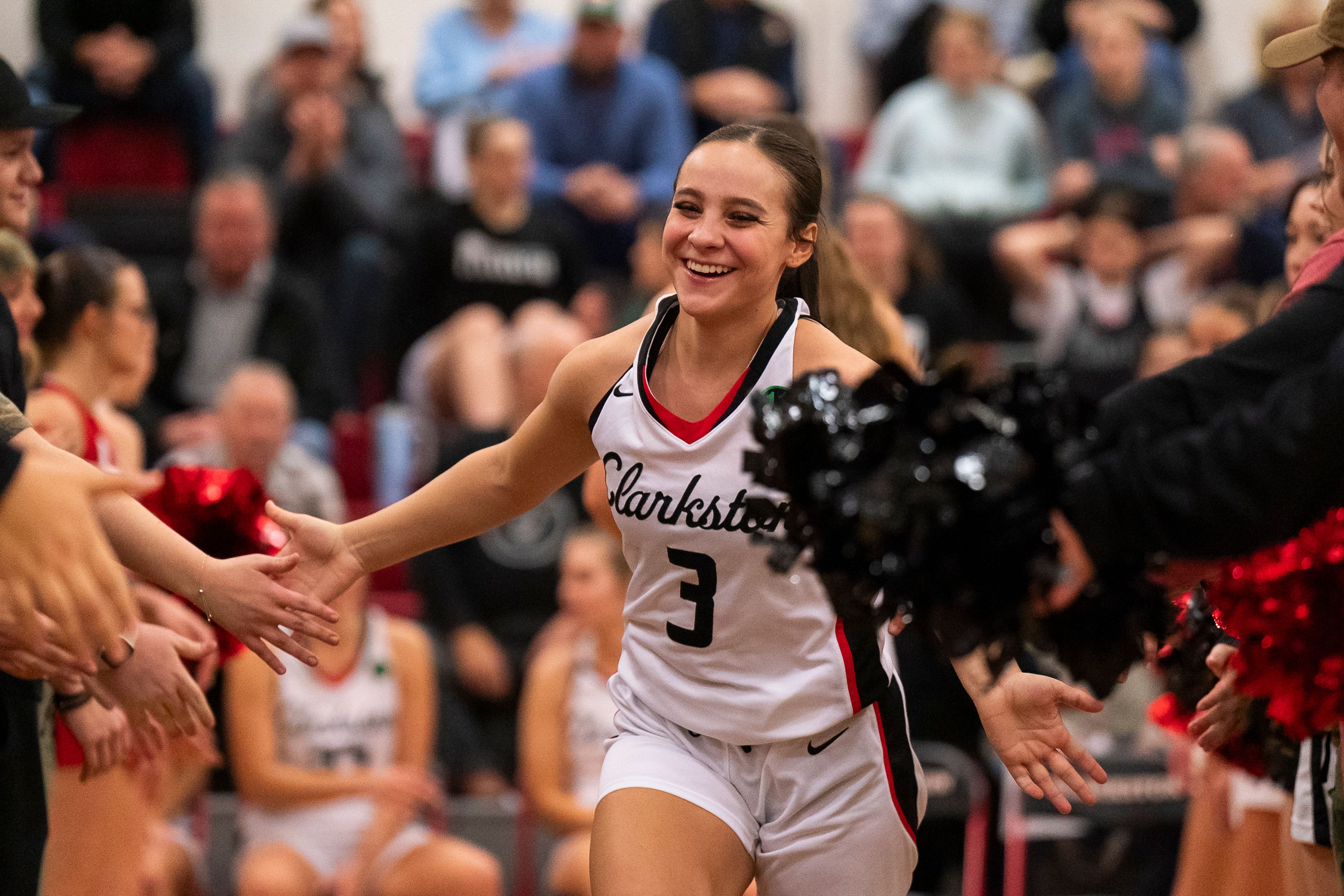 Clarkston’s Kendall Wallace (3) high-fives students and cheerleaders as she is being introduced before their game against West Valley on Jan. 9 at Clarkston High School.