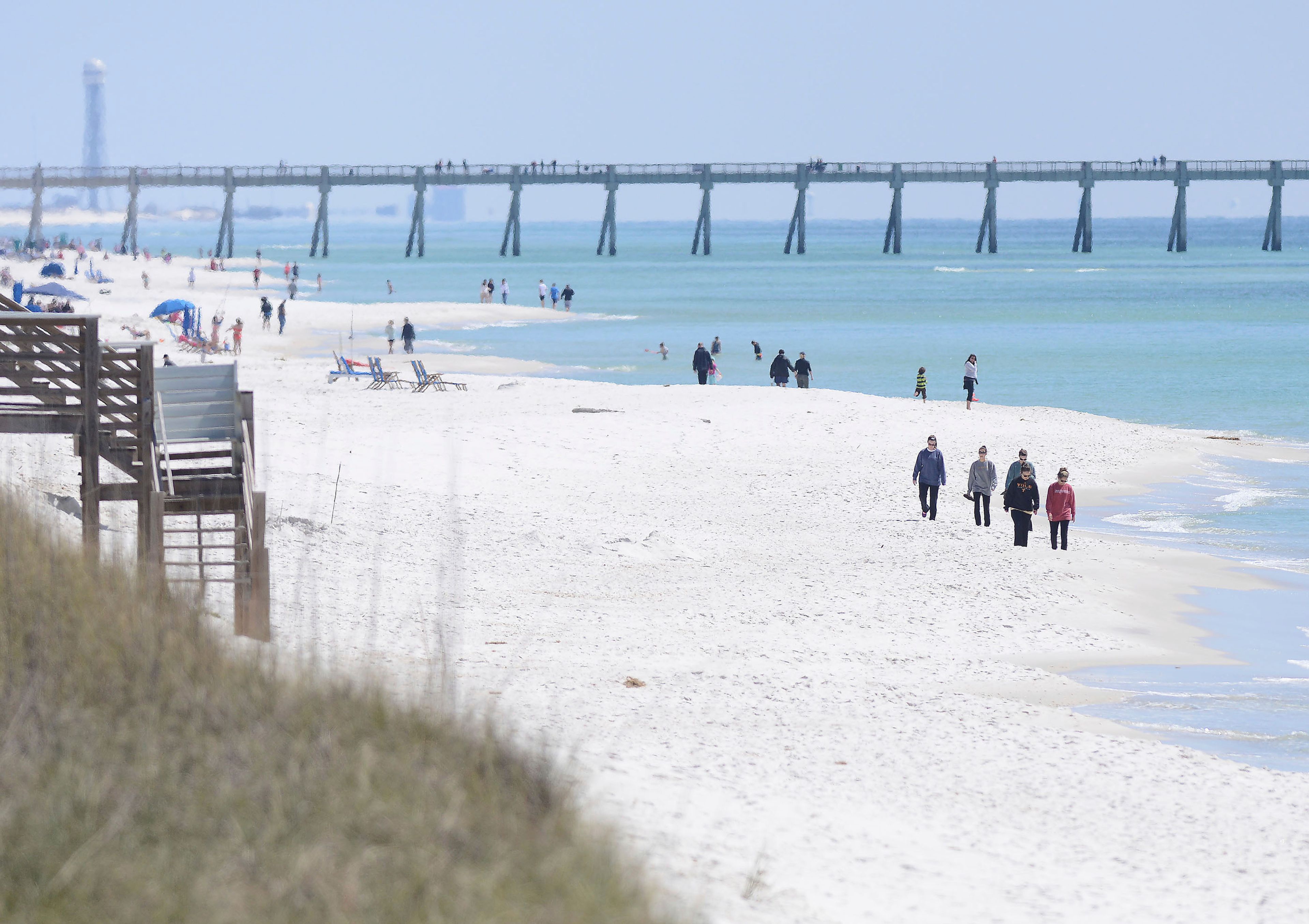 FILE - People walk along the shoreline in Navarre Beach, Fla., on Wednesday March 27, 2013. Authorities are warning of shark dangers this weekend along Florida’s Gulf Coast, where three people were hurt in two separate shark attacks Friday, June 7, 2024.