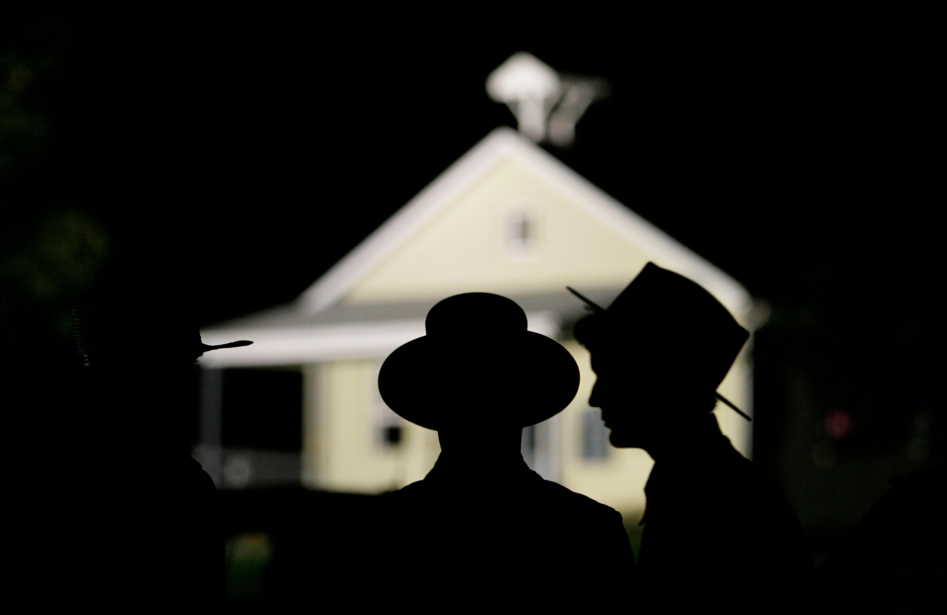 FILE - Amish men are seen in front of the schoolhouse where a gunman killed several people and injured others in Nickel Mines, Pa. Oct. 2, 2006.