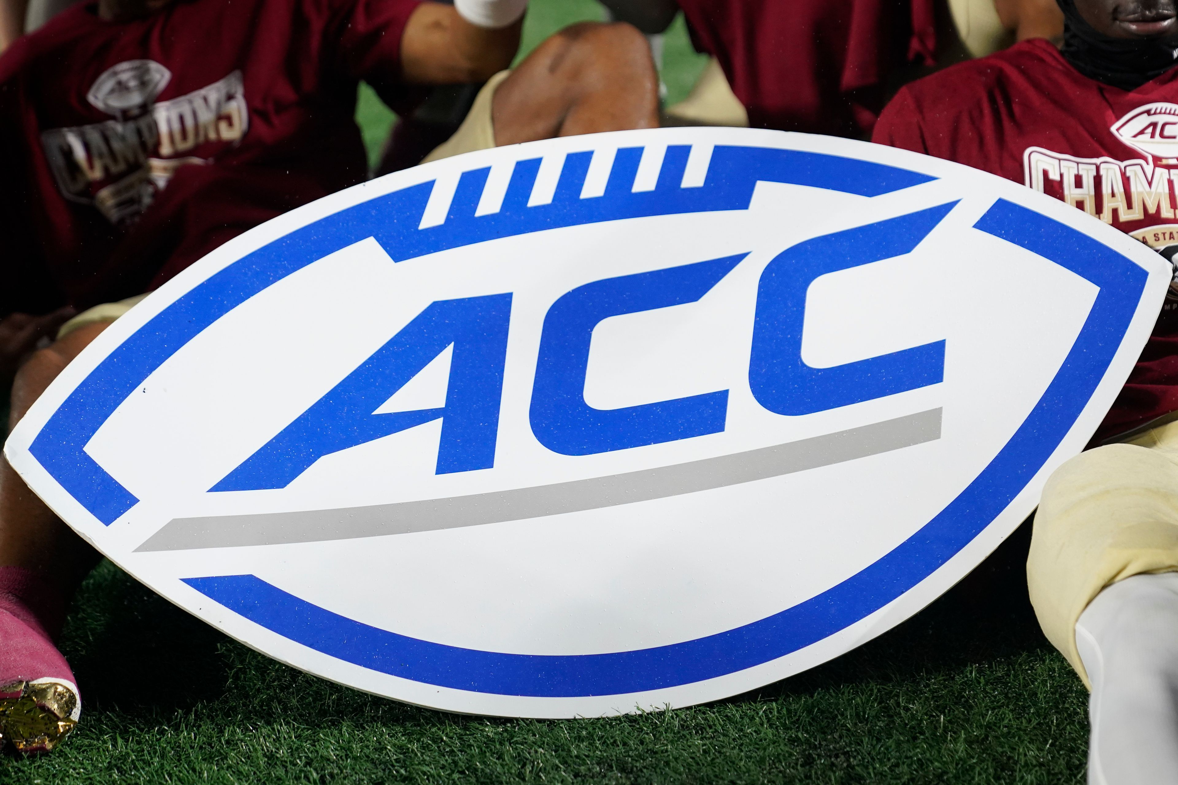 FILE - An Atlantic Coast Conference sign is displayed by Florida State players after the team's win over Louisville in the ACC championship NCAA college football game Dec. 2, 2023, in Charlotte, N.C. The NCAA and the nation's five biggest conferences have agreed to pay nearly $2.8 billion to settle a host of antitrust claims,a monumental decision that sets the stage for a groundbreaking revenue-sharing model that could start directing millions of dollars directly to athletes as soon as the 2025 fall semester.