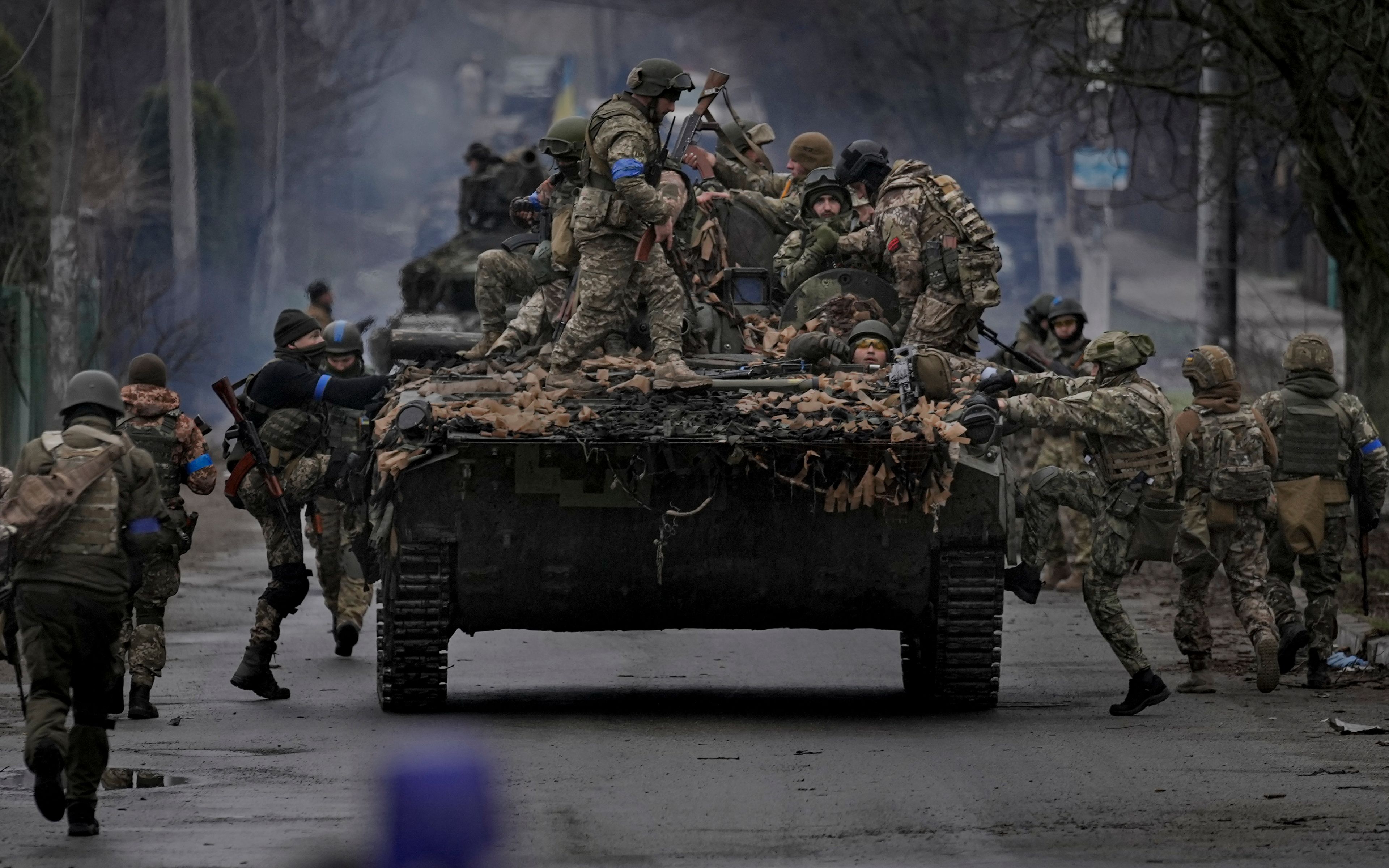 Ukrainian servicemen climb on a fighting vehicle outside Kyiv, Ukraine, Saturday, April 2, 2022. As Russian forces pull back from Ukraine's capital region, retreating troops are creating a "catastrophic" situation for civilians by leaving mines around homes, abandoned equipment and "even the bodies of those killed," President Volodymyr Zelenskyy warned Saturday. (AP Photo/Vadim Ghirda)