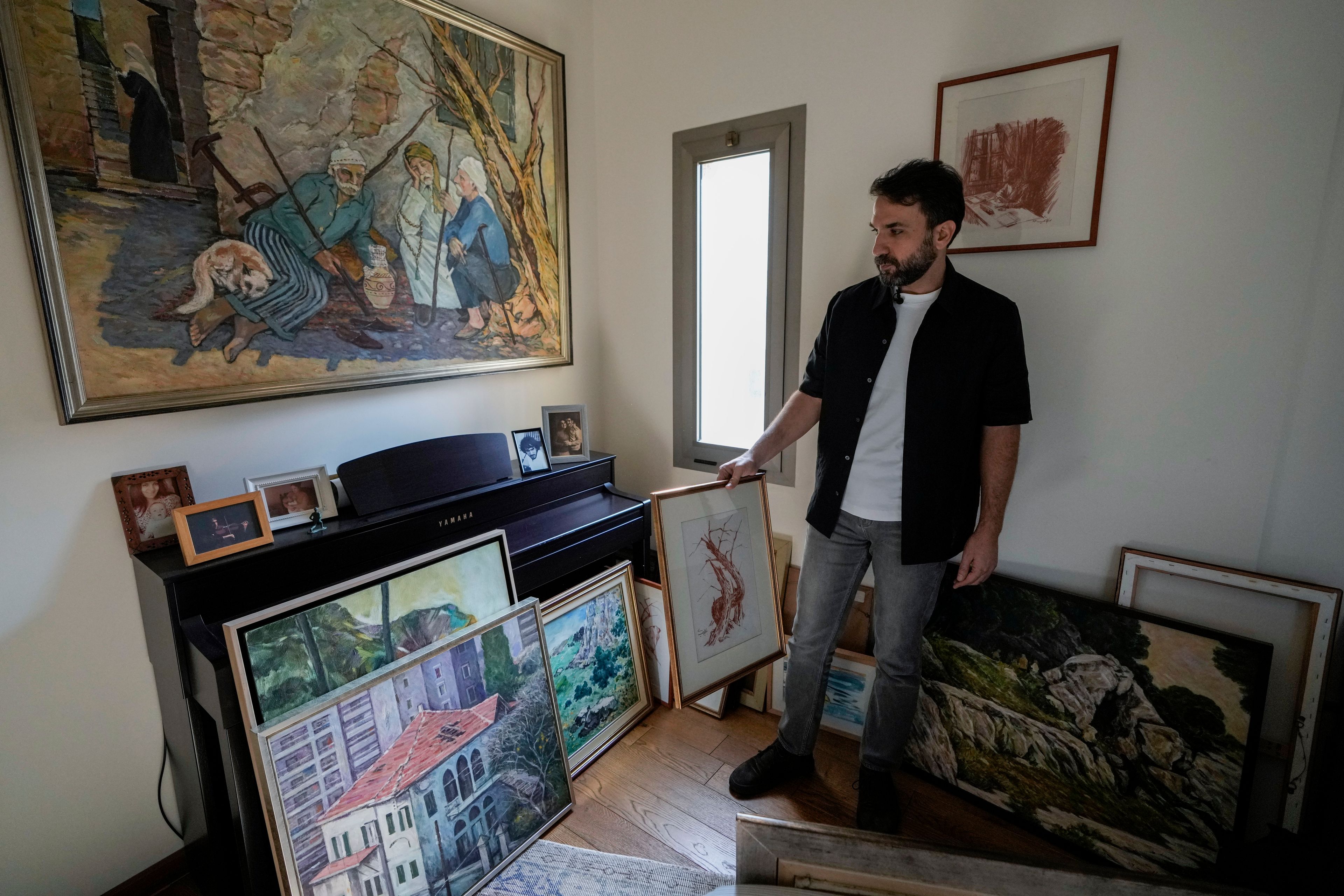 Lubnan Baalbaki shows his father's paintings during an interview with The Associated Press at his house in Geitawi, Beirut, Lebanon, Thursday, Oct. 31, 2024. (AP Photo/Bilal Hussein)