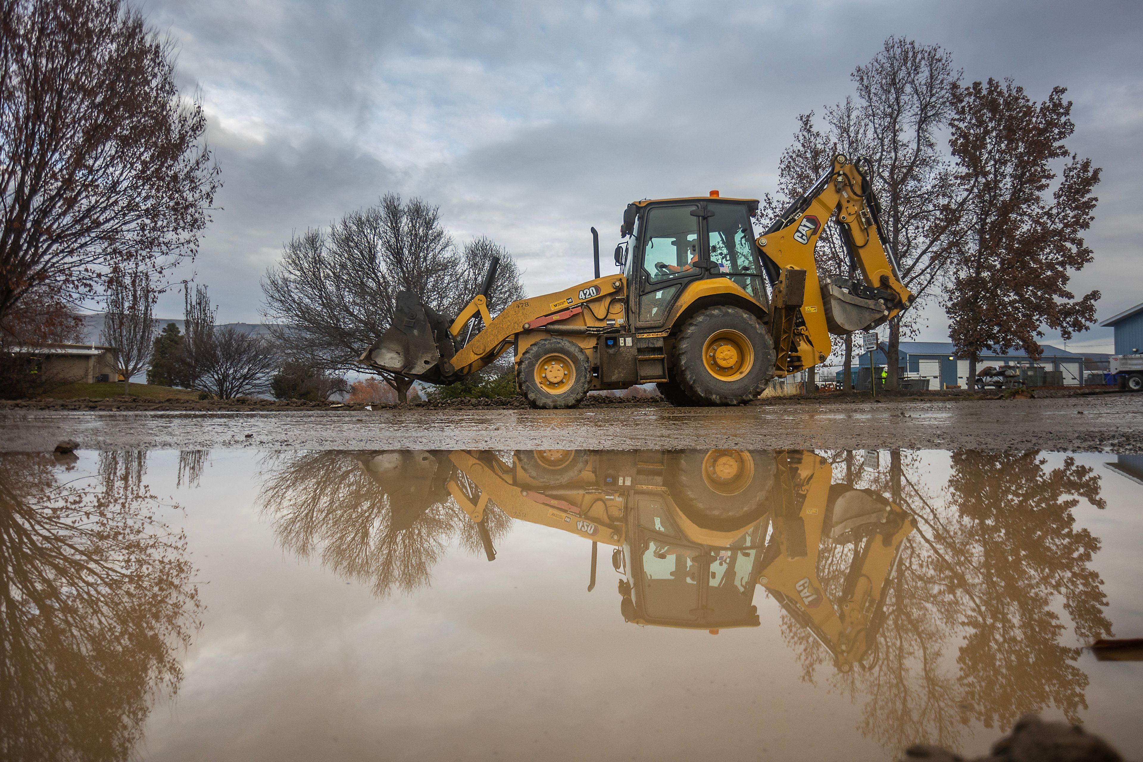 A bulldozer moves past a large puddle as it works on clean up after a water reservoir at the corner of 16th Avenue and 29th Street burst in the early hours of Wednesday morning in Lewiston.