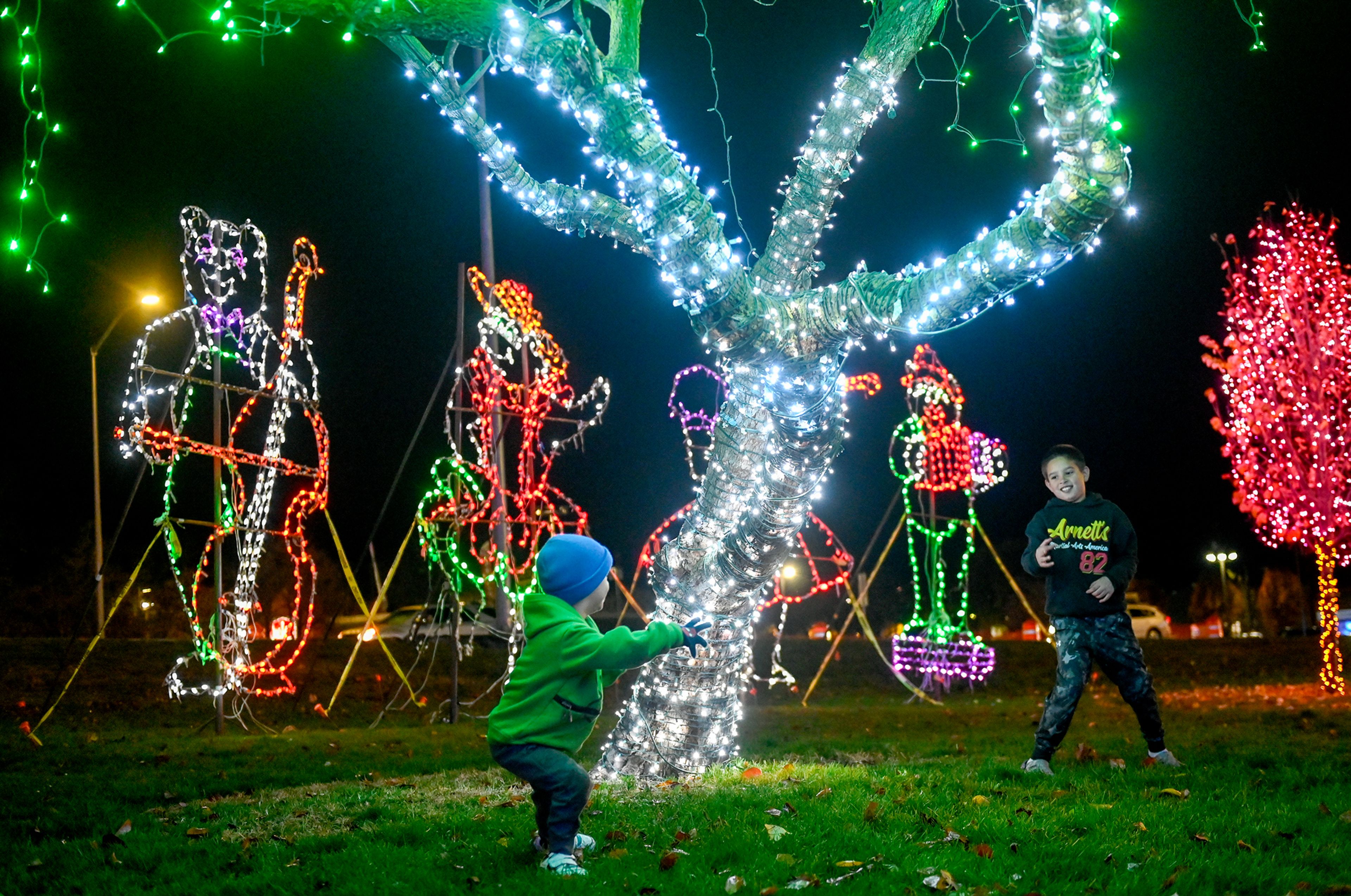 Levi, left, 4, and Louis, 8, play tag under the lights Saturday after the opening of the Winter Spirit holiday display at Locomotive Park in Lewiston.