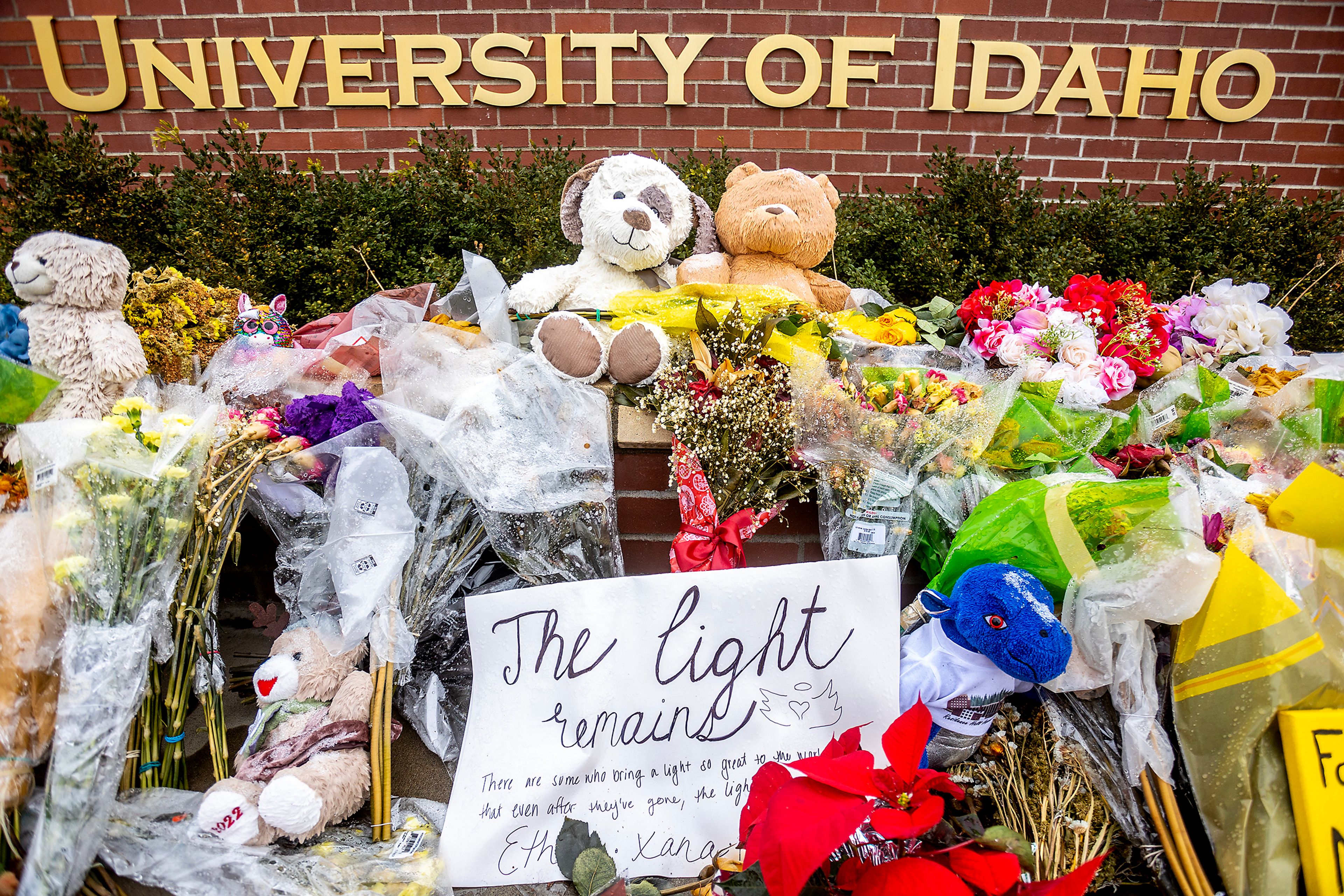 Flowers, stuffed animals and signs sit around a University of Idaho sign in Moscow on Saturday, Nov. 26.