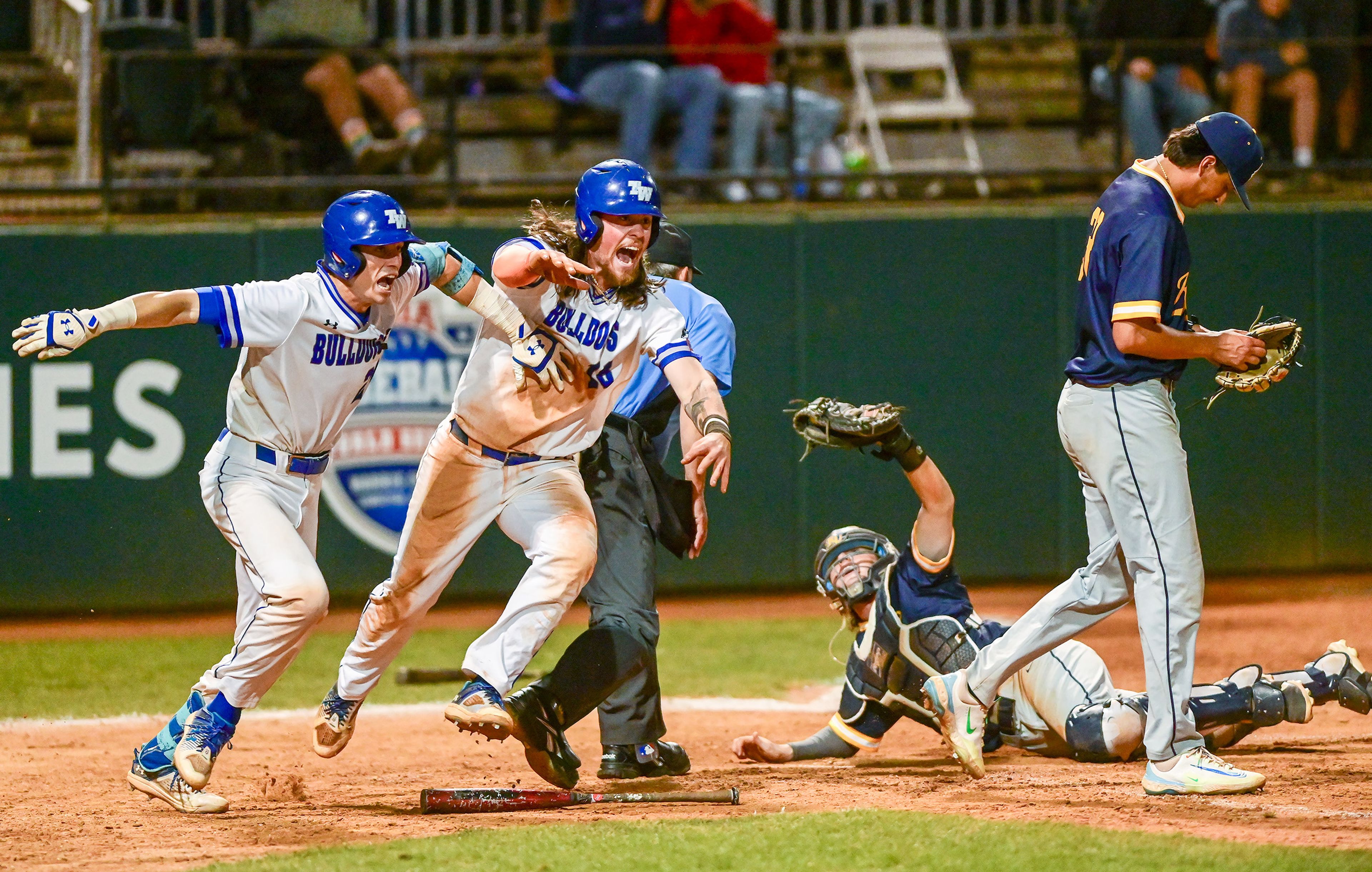 Tennessee Wesleyan’s Daniel Stewart, left, and Evan Magill begin running to the outfield to celebrate Kruise Newman’s hit that took Magill to the home plate, winning Game 18 of the NAIA World Series over Reinhardt at Harris Field in Lewiston on Thursday. Reinhardt catcher Matty Maurer raises his glove to the umpire as pitcher Andrew Herbert walks away from the plate.