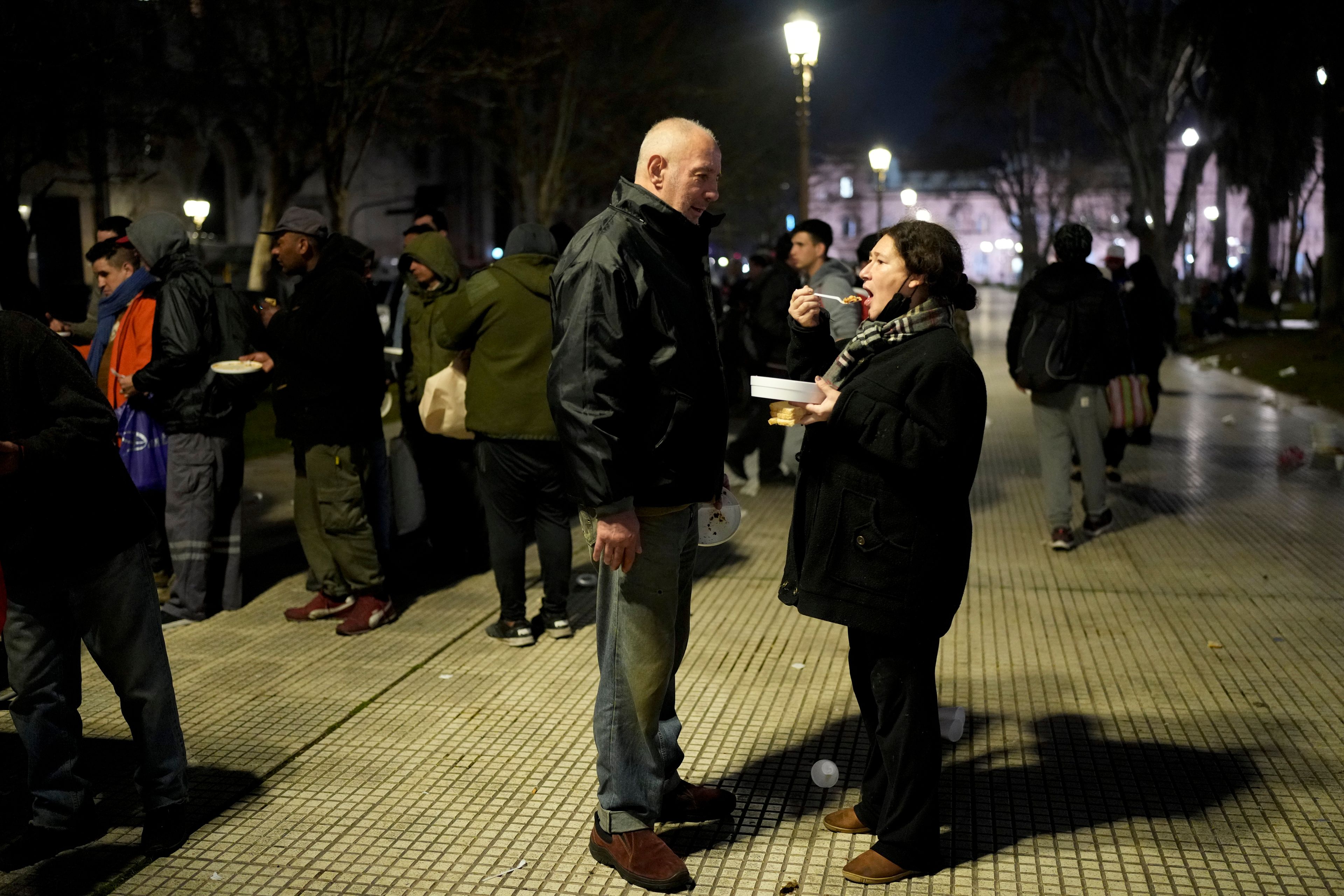 Debora Paola Galluccio eats her one meal of the day from a community kitchen next to her partner Marcelo Díaz in Buenos Aires, Argentina, Monday, Sept. 9, 2024. (AP Photo/Natacha Pisarenko)