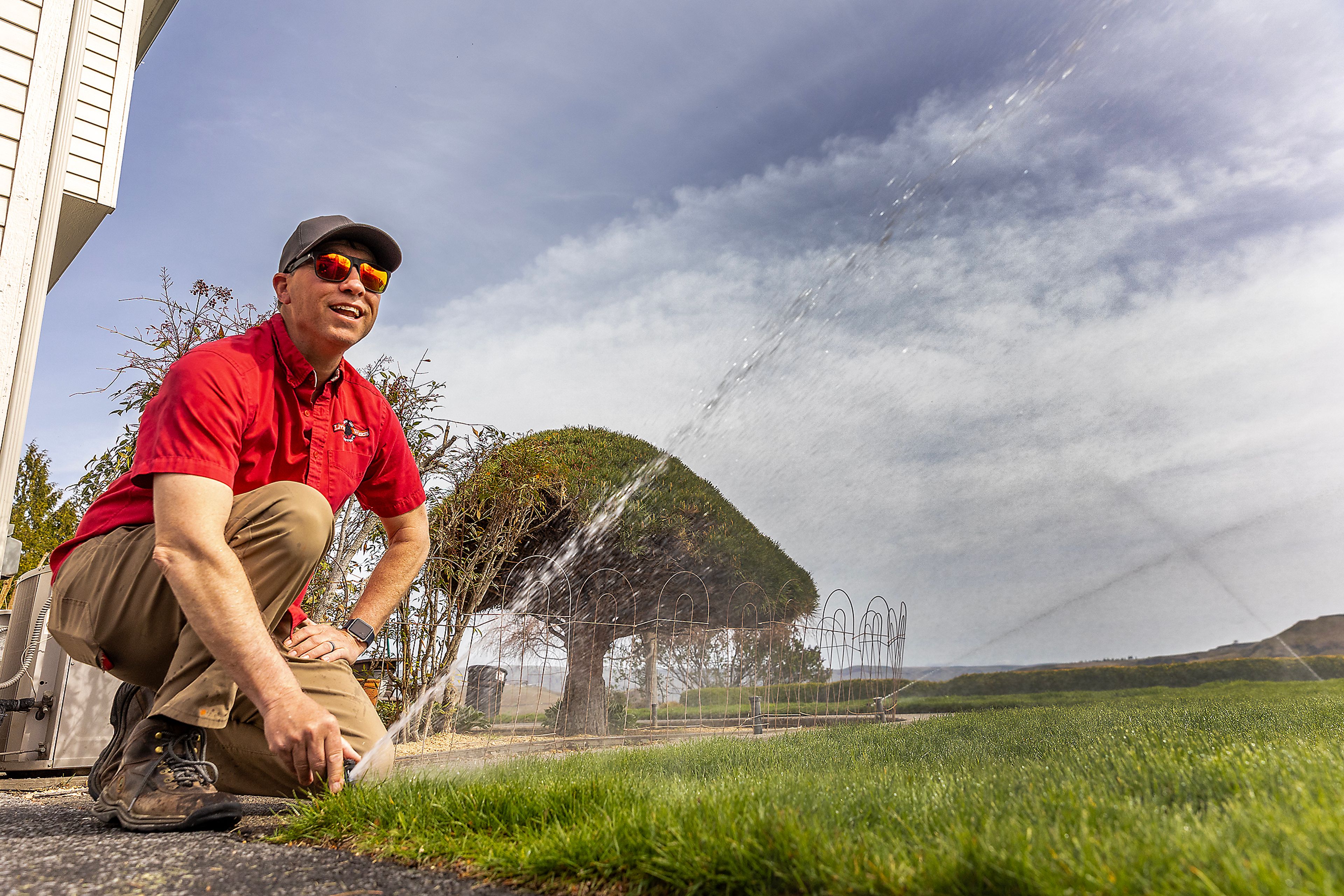 Brian McKarcher adjusts a sprinkler at his home Thursday.