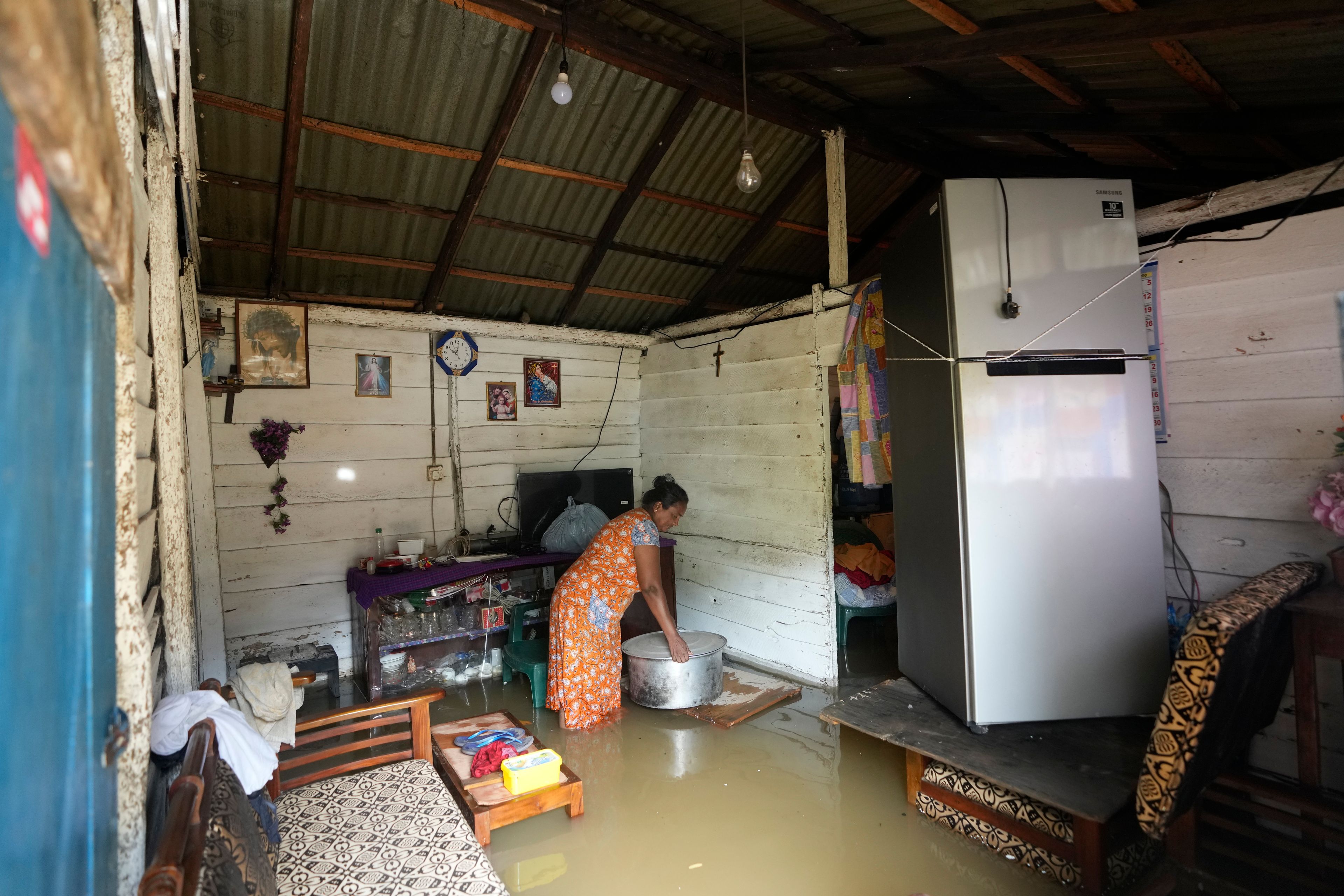 A women removes the utensils from her house submerged with floodwaters in Kelaniya, a suburb of Colombo, Sri Lanka, Monday, June 3, 2024. Sri Lanka closed schools on Monday as heavy rains triggered floods and mudslides in many parts of the island nation, killing at least 10 people while six others have gone missing, officials said.