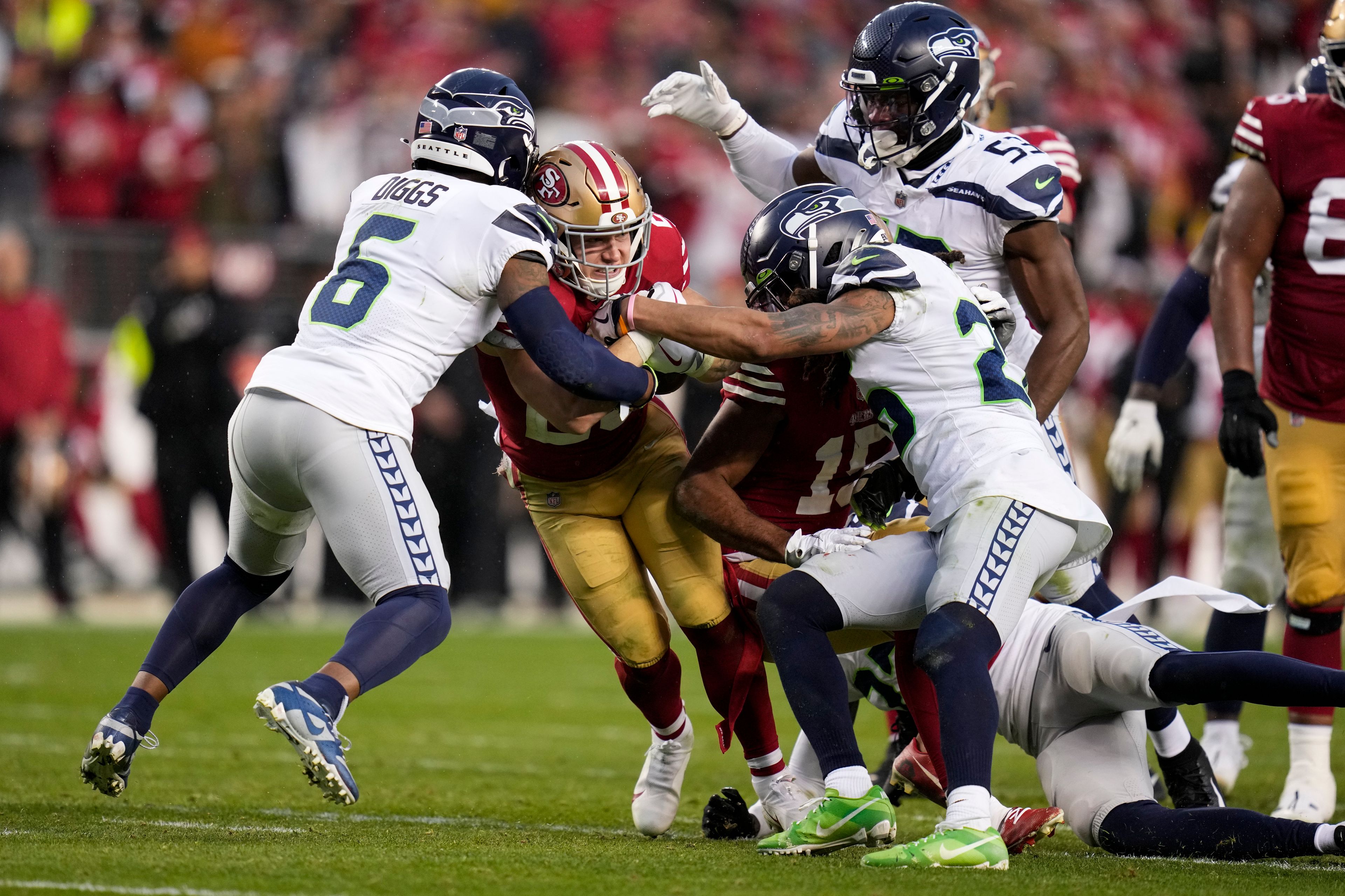 San Francisco 49ers running back Christian McCaffrey, middle, runs against Seattle Seahawks safety Quandre Diggs (6), linebacker Boye Mafe (53) and safety Ryan Neal during the second half of during the second half of an NFL wild card playoff football game in Santa Clara, Calif., Saturday, Jan. 14, 2023. (AP Photo/Godofredo A. Vásquez)