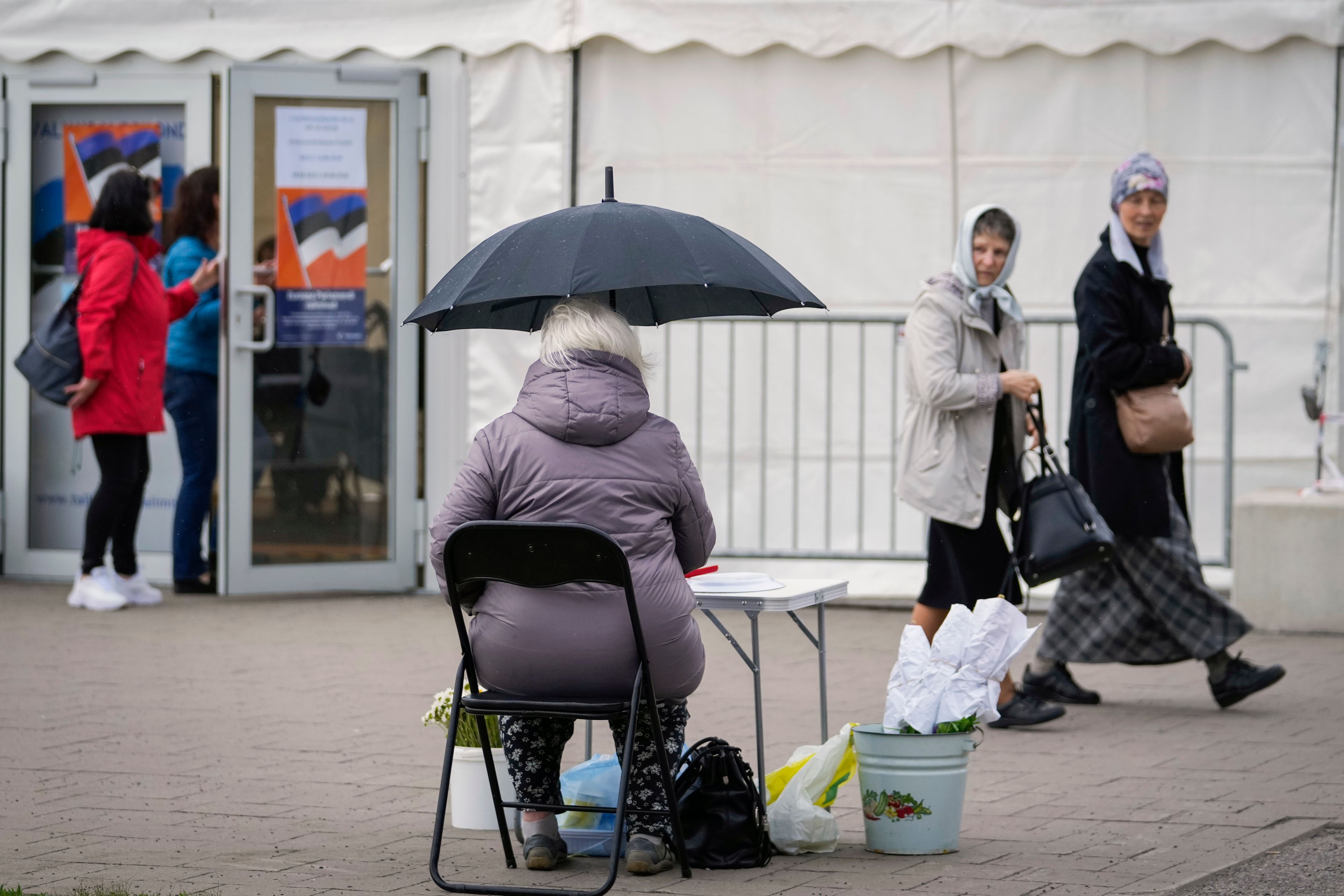 A woman sells flowers and berries with the mobile polling station on the background during the European Parliament election in Tallinn, Estonia, Sunday, June 9, 2024. Polling stations opened across Europe on Sunday as voters from 20 countries cast ballots in elections that are expected to shift the European Union's parliament to the right and could reshape the future direction of the world's biggest trading bloc.