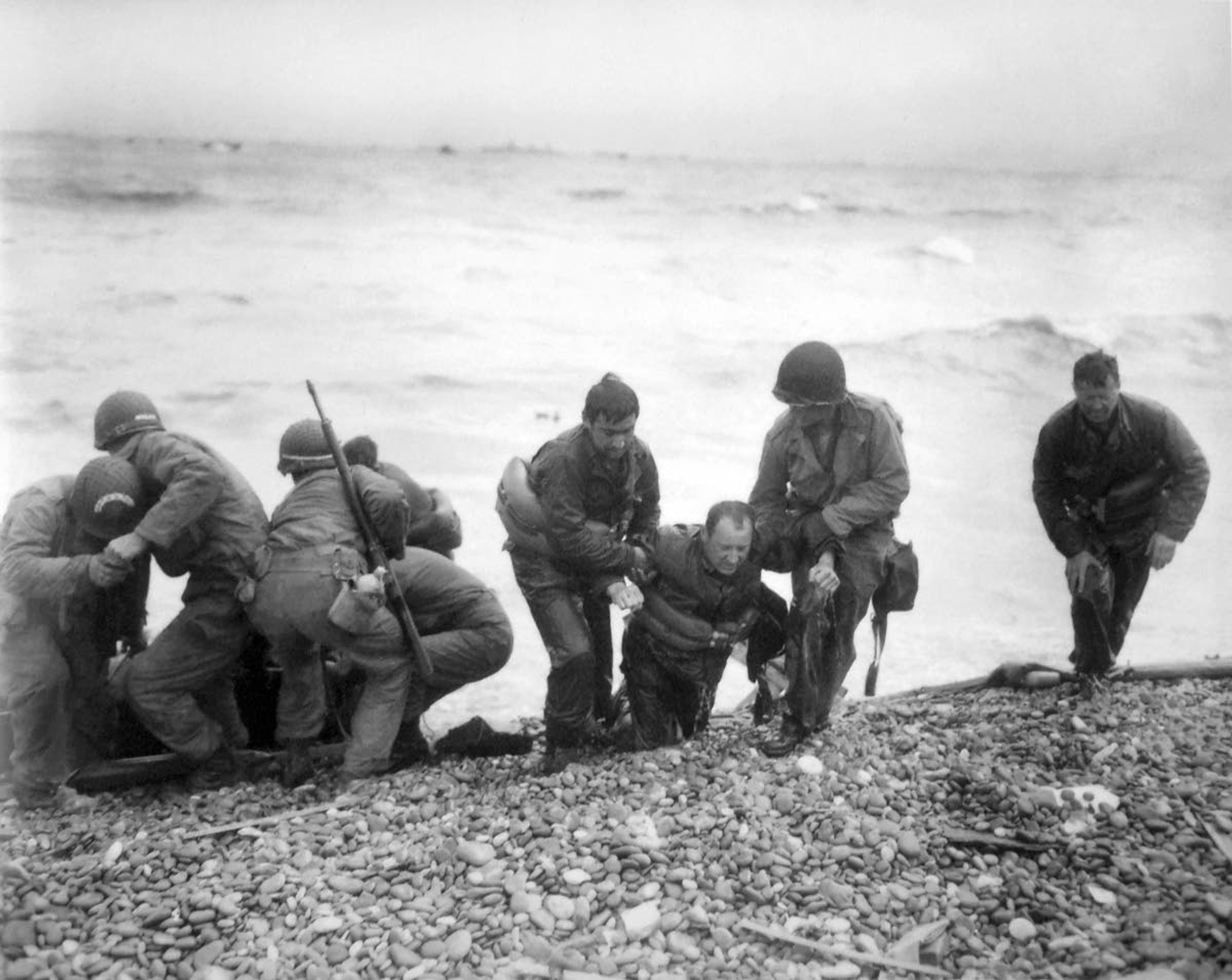 FILE - In this June 6, 1944, file photo, members of an American landing unit help their comrades ashore during the Normandy invasion. The men reached the zone code-named Utah Beach, near Sainte- Mere-Eglise, on a life raft after their landing craft was hit and sunk by German coastal defenses. (Louis Weintraub/Pool Photo via AP, File)