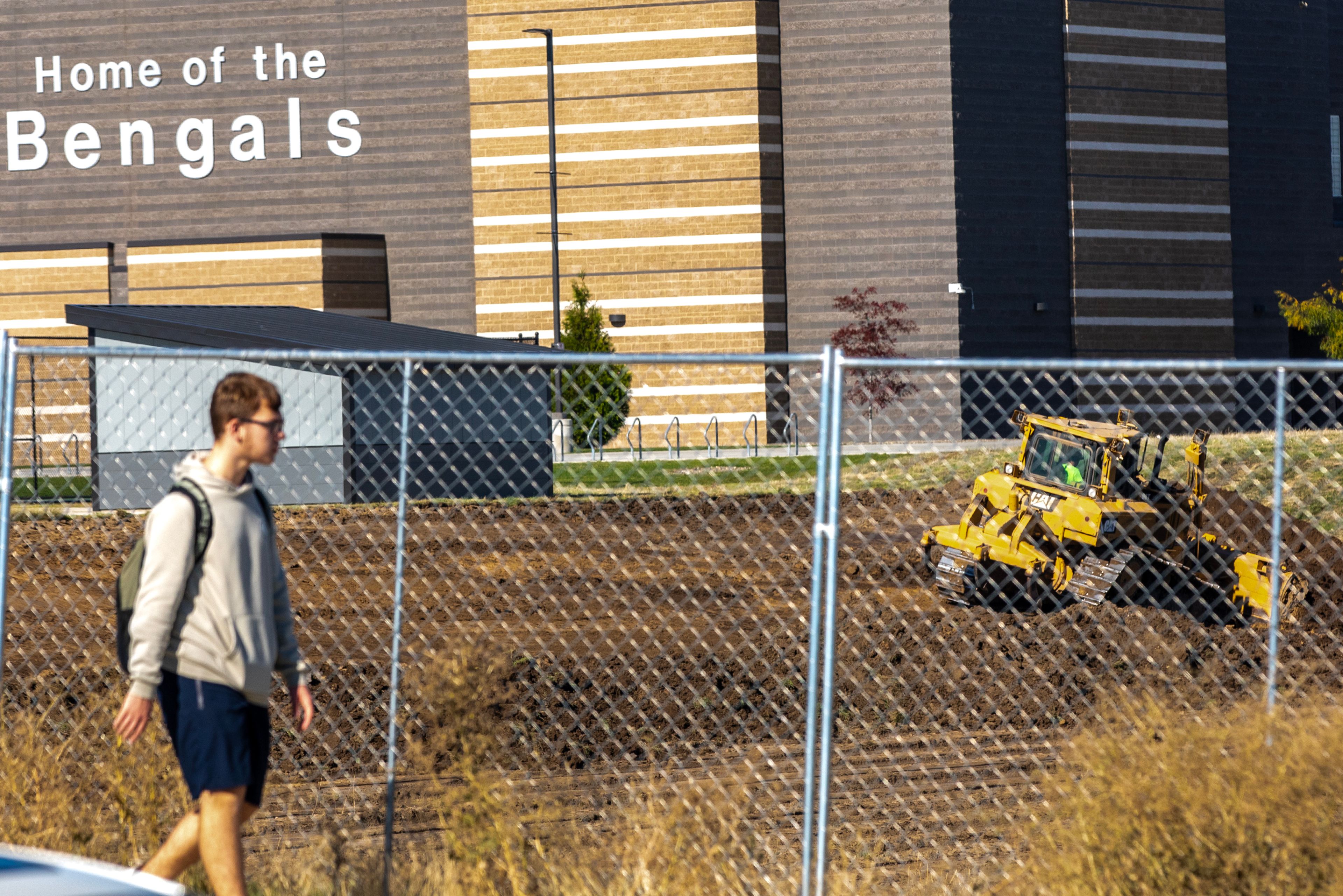 A student walks past what will be the future athletic fields at Lewiston High School as a vehicles moves dirt Wednesday in Lewiston.