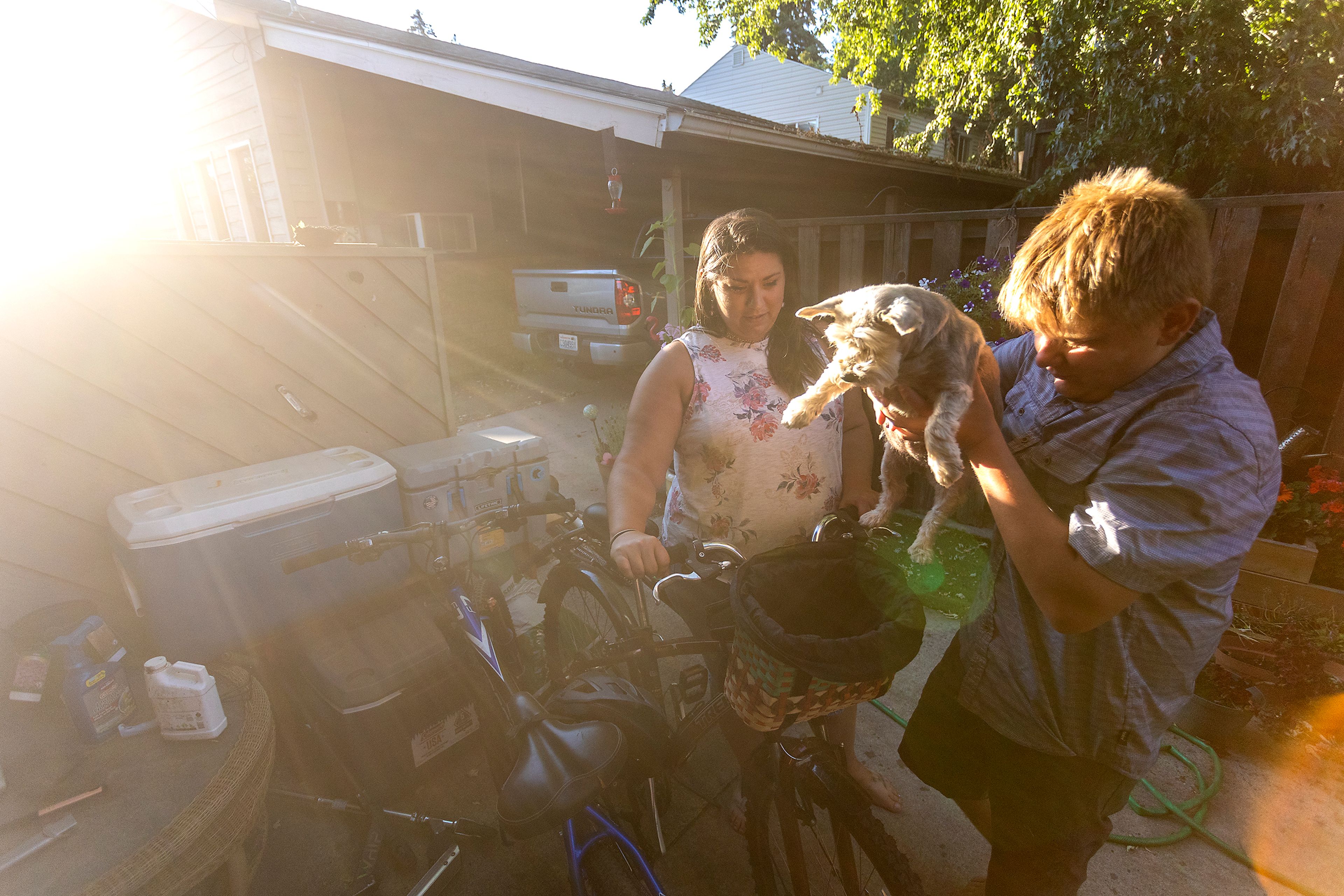 Tony Poulsen places their dog, Gracey, in the basket on his mother Aimee Martinez’s bike on Friday.