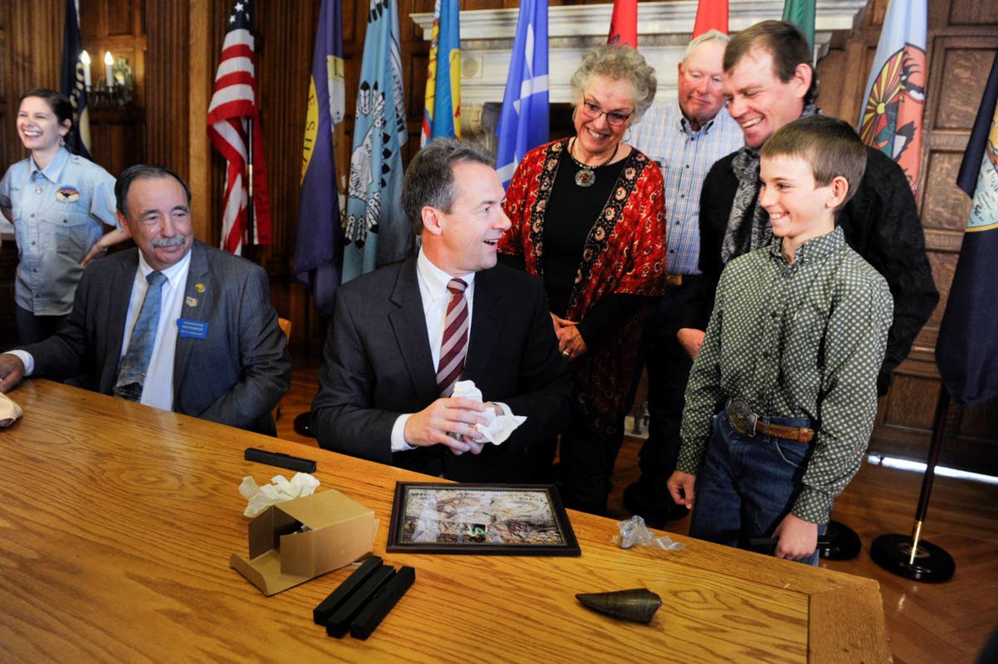 Luke Phipps, 12, presents Montana Gov. Steve Bullock with a fossilized rib and tail vertebrae from a triceratops Tuesday at the State Capitol in Helena, Mont., after the governor signed a bill clarifying fossil ownership in the state.