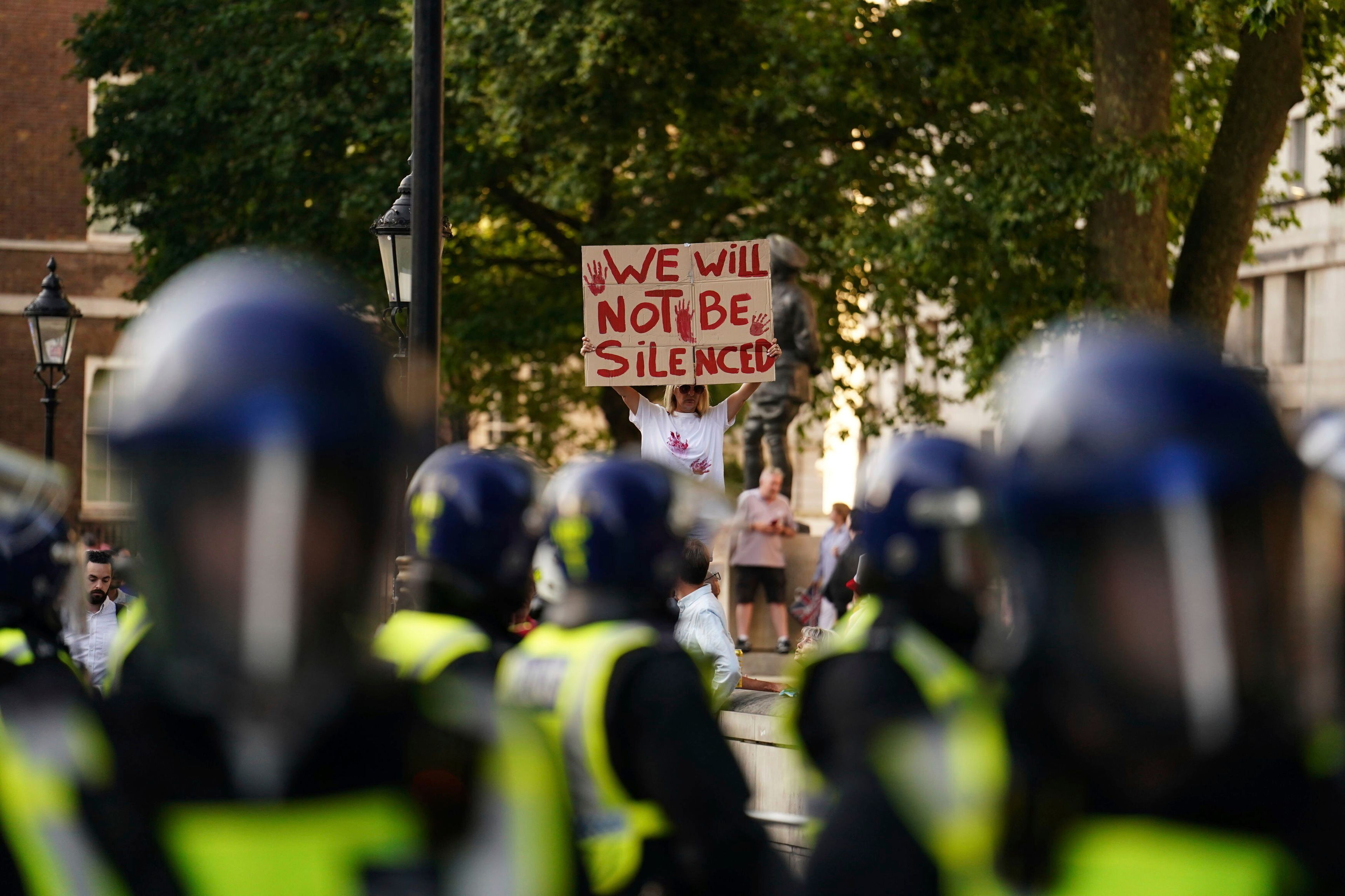 A protester holds up a sign police officers gather during the "Enough is Enough" protest in Whitehall, London, Wednesday July 31, 2024, following the fatal stabbing of three children at a Taylor Swift-themed summer holiday dance and yoga class on Monday in Southport. (Jordan Pettitt/PA via AP)