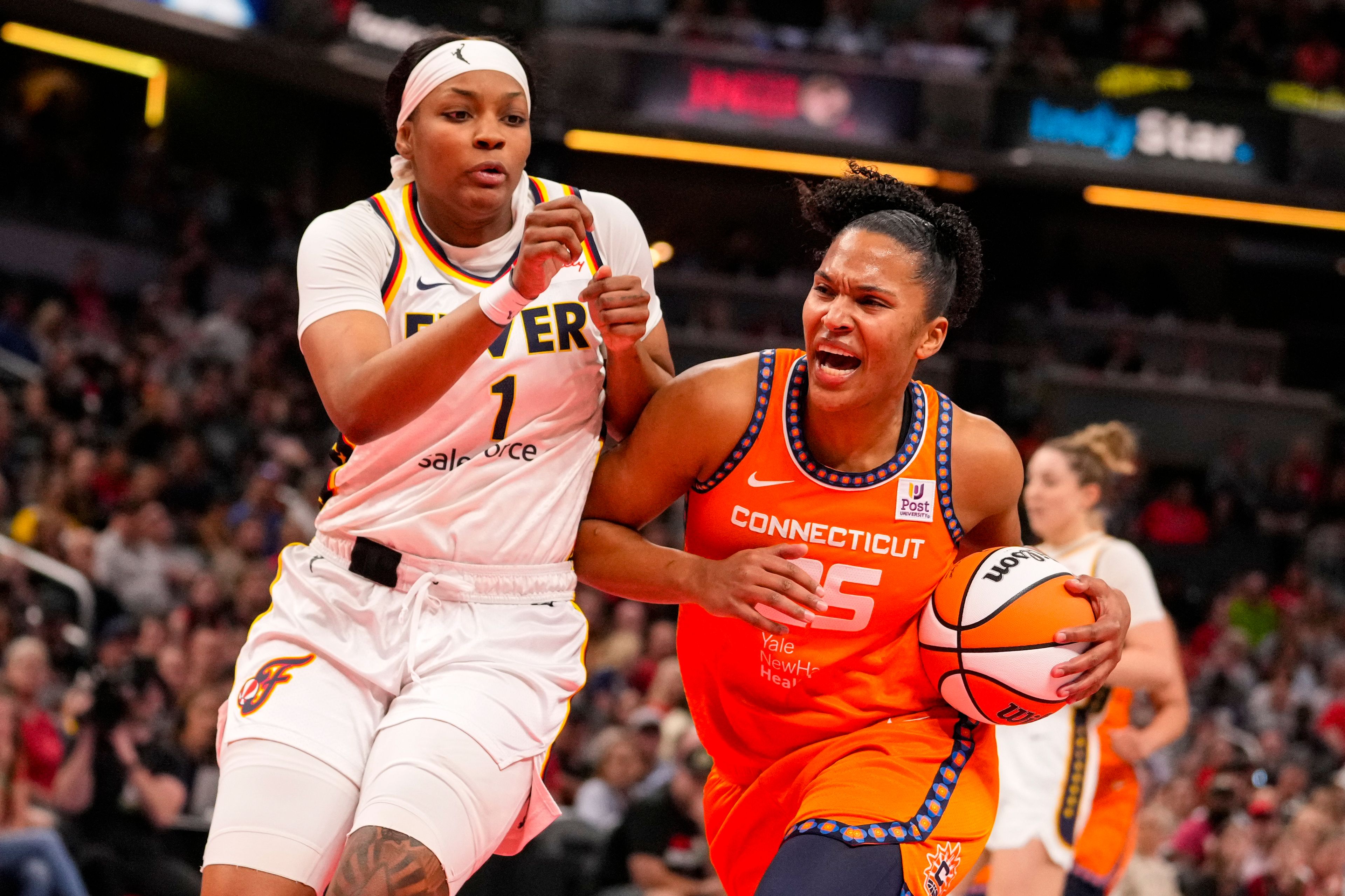 Connecticut Sun forward Alyssa Thomas (25) drives on Indiana Fever forward NaLyssa Smith (1) in the first half of a WNBA basketball game in Indianapolis, Monday, May 20, 2024.