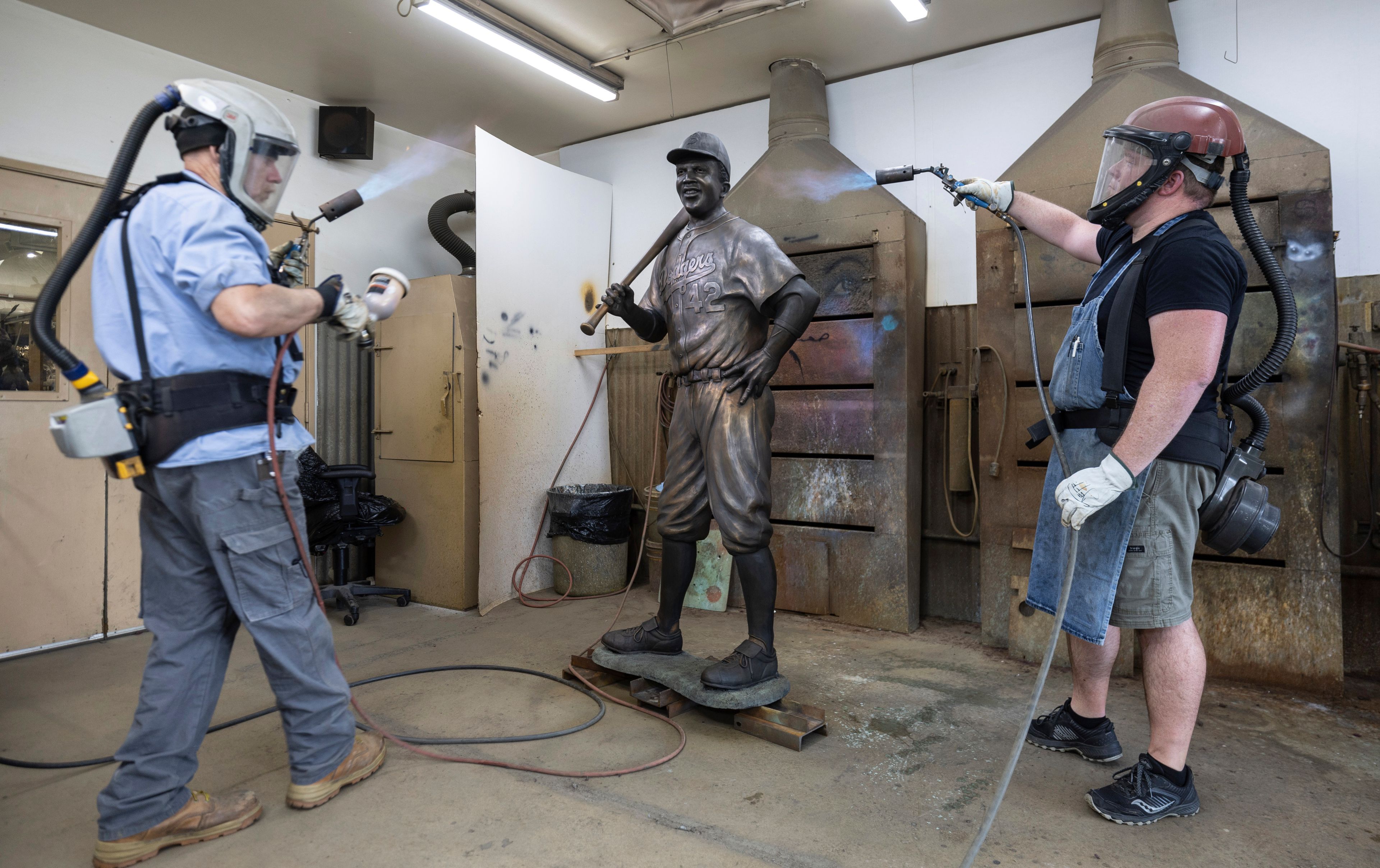 Nate Ford, left, and Jeff Herndon apply finishing touches to a statue of baseball hall-of-famer and civil rights pioneer Jackie Robinson in Loveland, Colo., on Wednesday, July 24, 2024. (Travis Heying/The Wichita Eagle via AP)