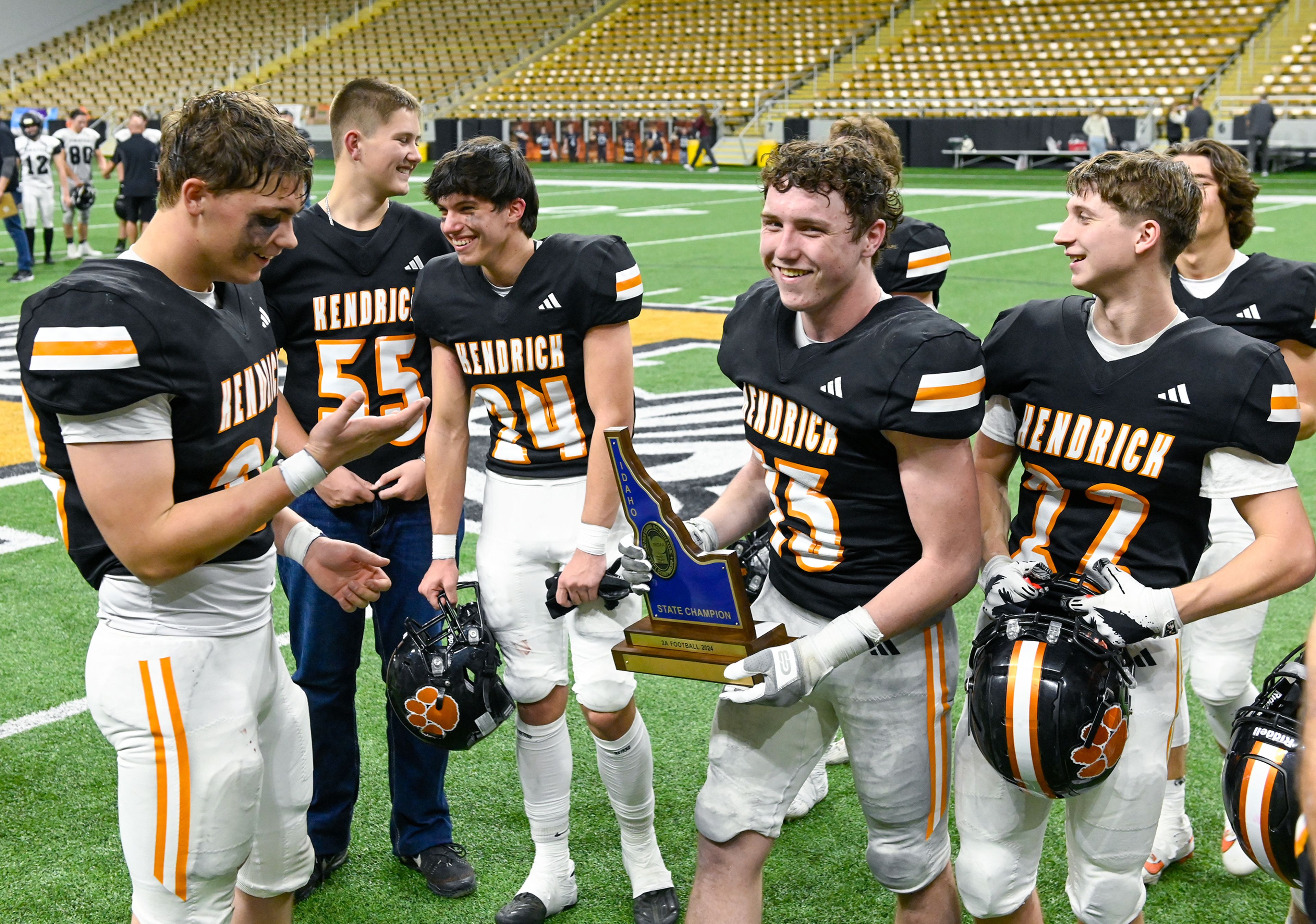 Kendrick players walk off the field carrying the trophy for their Idaho Class 2A state championship win over Butte County Friday at the P1FCU Kibbie Dome in Moscow.