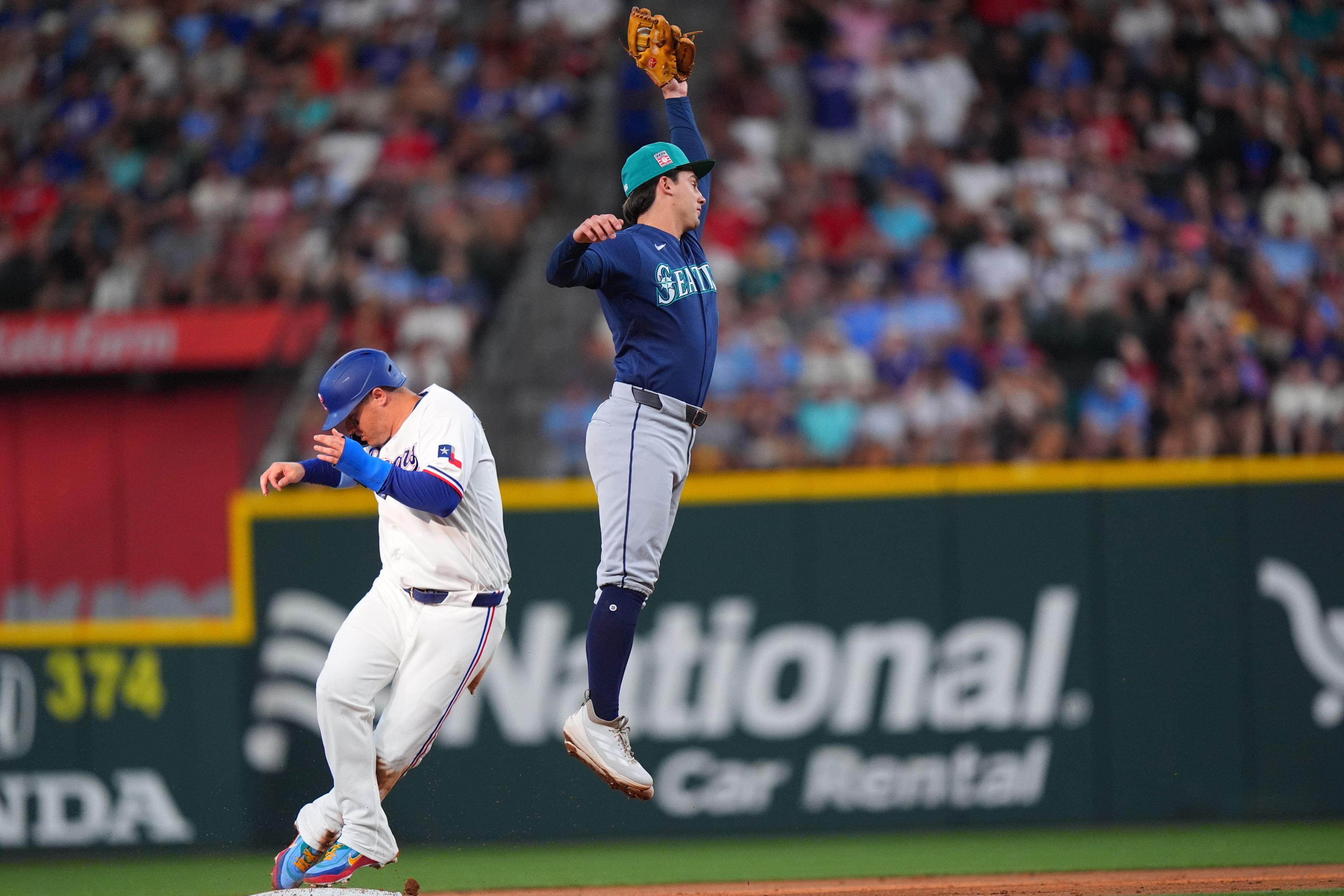 The Rangers’ Joc Pederson, left, steals second base against Seattle Mariners second baseman Cole Young during the second inning of a baseball game, Saturday, in Arlington, Texas. 