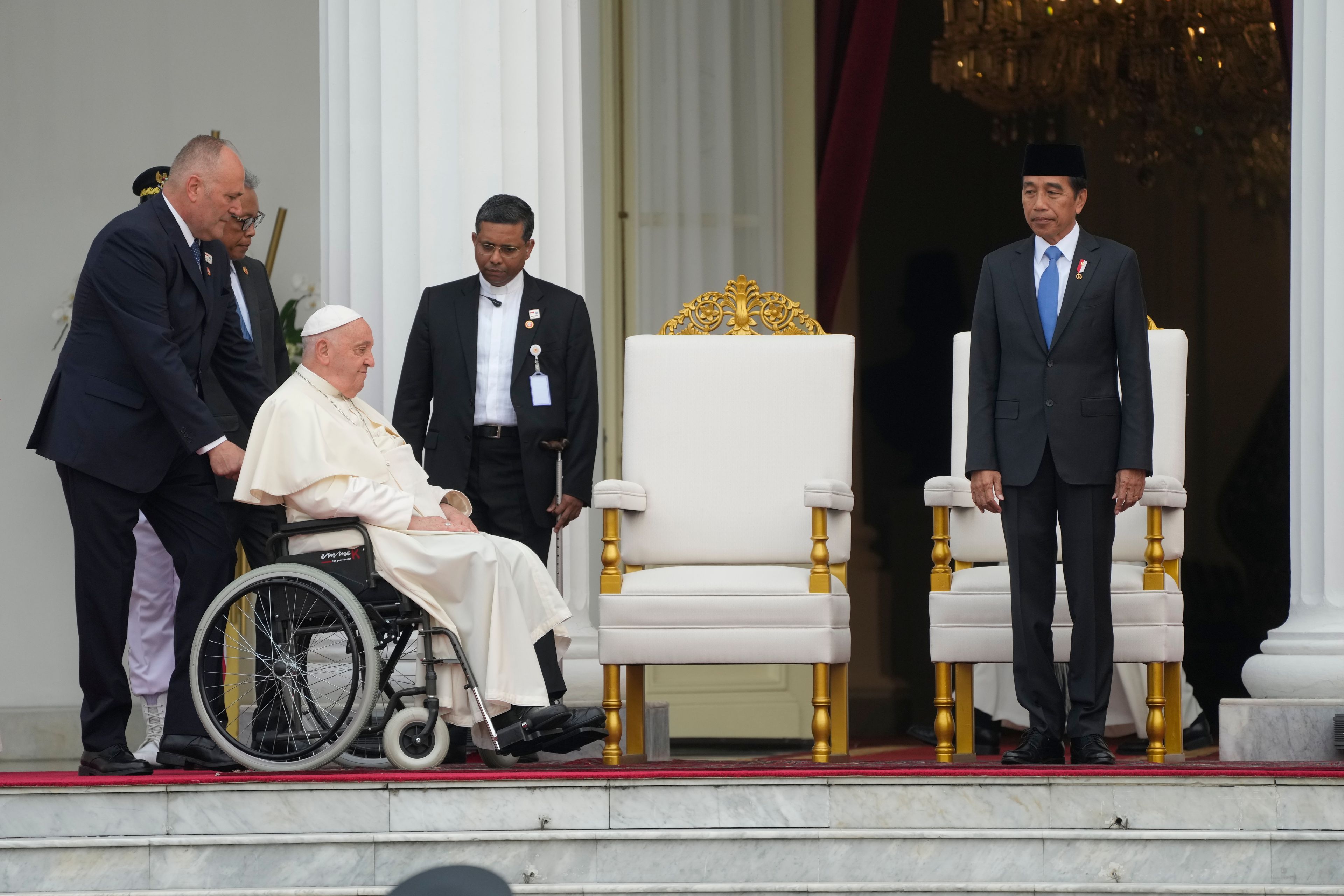 Indonesian President Joko Widodo, right, receives Pope Francis, helped on a wheelchair by assistant Piergiorgio Zanetti, at Istana Merdeka Presidential Palace in Jakarta, Wednesday, Sept. 4, 2024. Pope Francis is opening his visit to Indonesia with a packed first day Wednesday, meeting political and religious leaders and setting a rigorous pace for an 11-day, four-nation trip through tropical Asia and Oceania that will test his stamina and health.