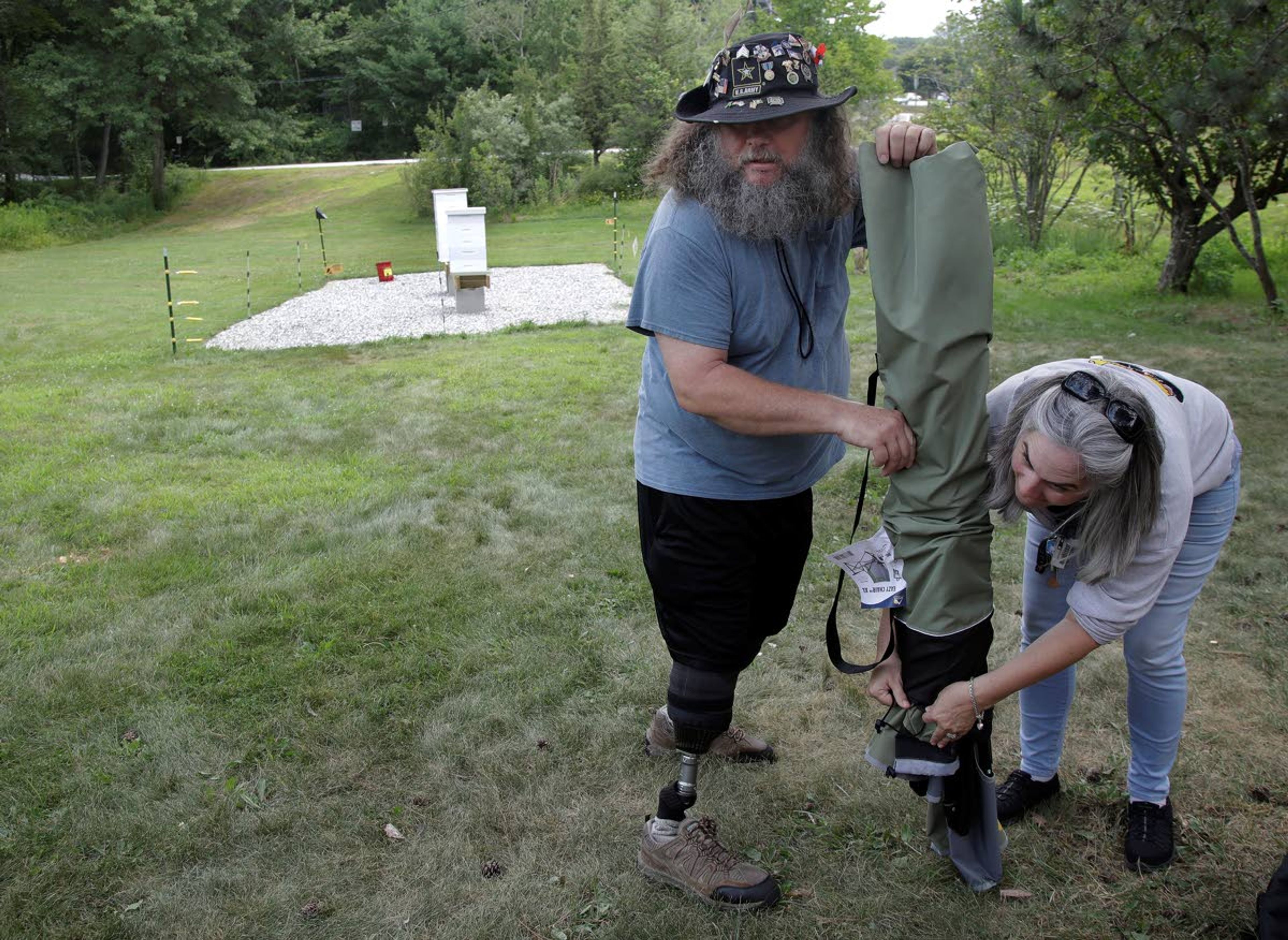 In this Aug. 7, 2019 photo, U.S. Army veterans Oscar Toce, left, and Wendi Zimmermann pack up after beekeeping activities at the Veterans Affairs' beehives in Manchester, N.H. A small but growing number of veterans around the country are turning to beekeeping as a potential treatment for anxiety, PTSD and other conditions. (AP Photo/Elise Amendola)