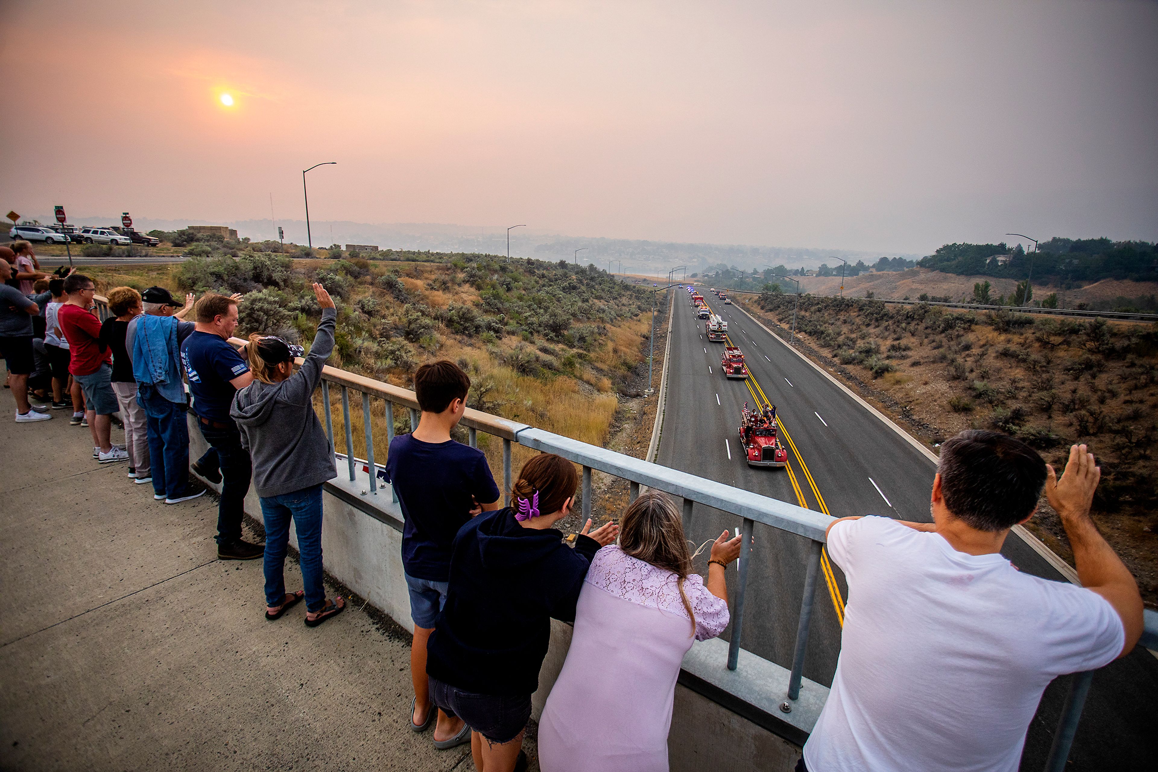 People wave Sunday from the Eighth Street bridge overlooking Bryden Canyon Road as first responders travel in a procession commemorating the anniversary of the Sept. 11, 2001, terrorist attack in New York City and Washington, D.C.