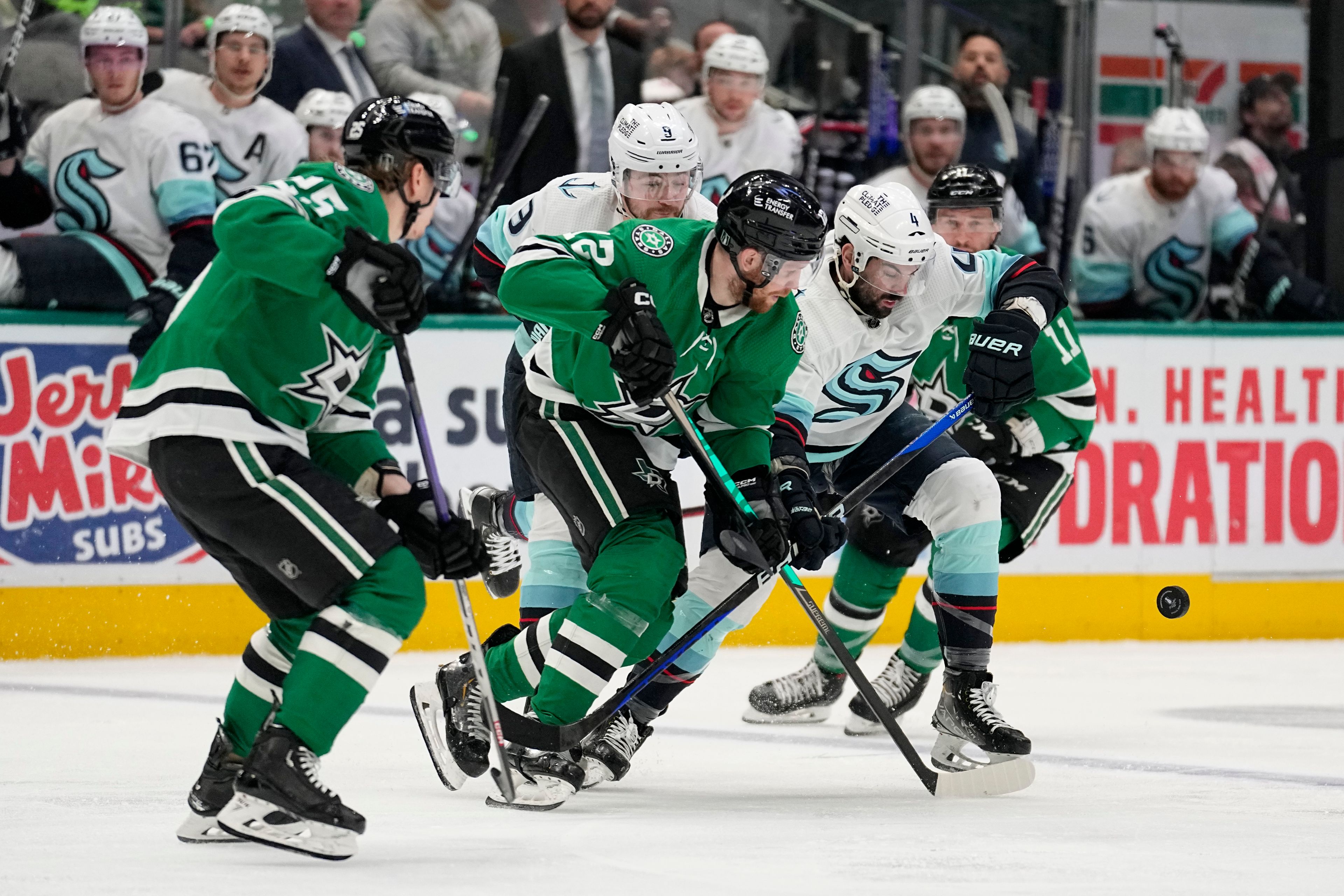 Seattle Kraken defenseman Justin Schultz (4) chases after control of the puck aginst Dallas Stars' Joel Kiviranta (25) and Radek Faksa (12) in the second period of Game 7 of an NHL hockey Stanley Cup second-round playoff series, Monday, May 15, 2023, in Dallas. (AP Photo/Tony Gutierrez)