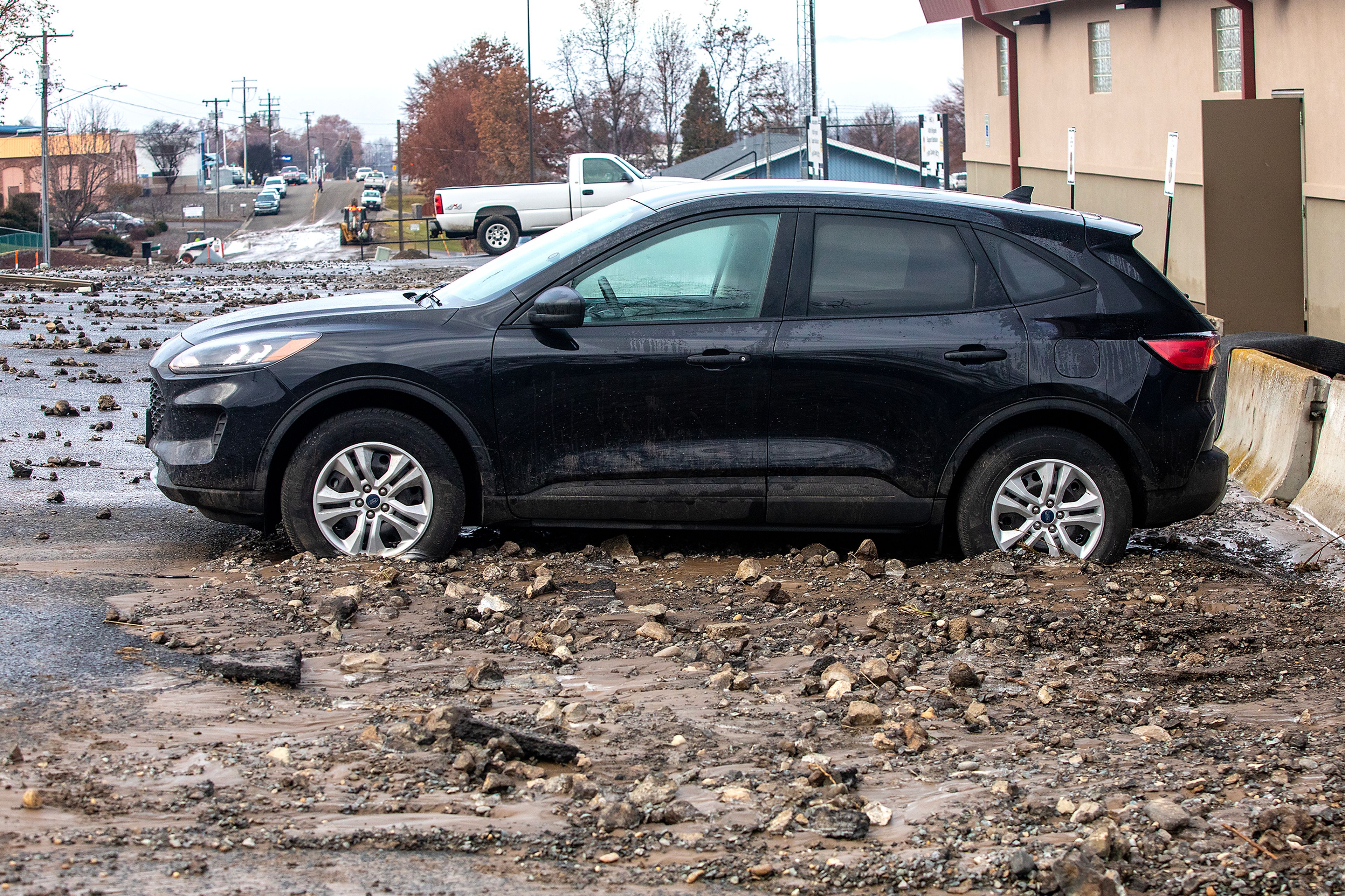 Debris sits around a car parked at the Idaho Army National Guard after a water reservoir at the corner of 16th Avenue and 29th Street burst in the early hours of Wednesday morning in Lewiston.