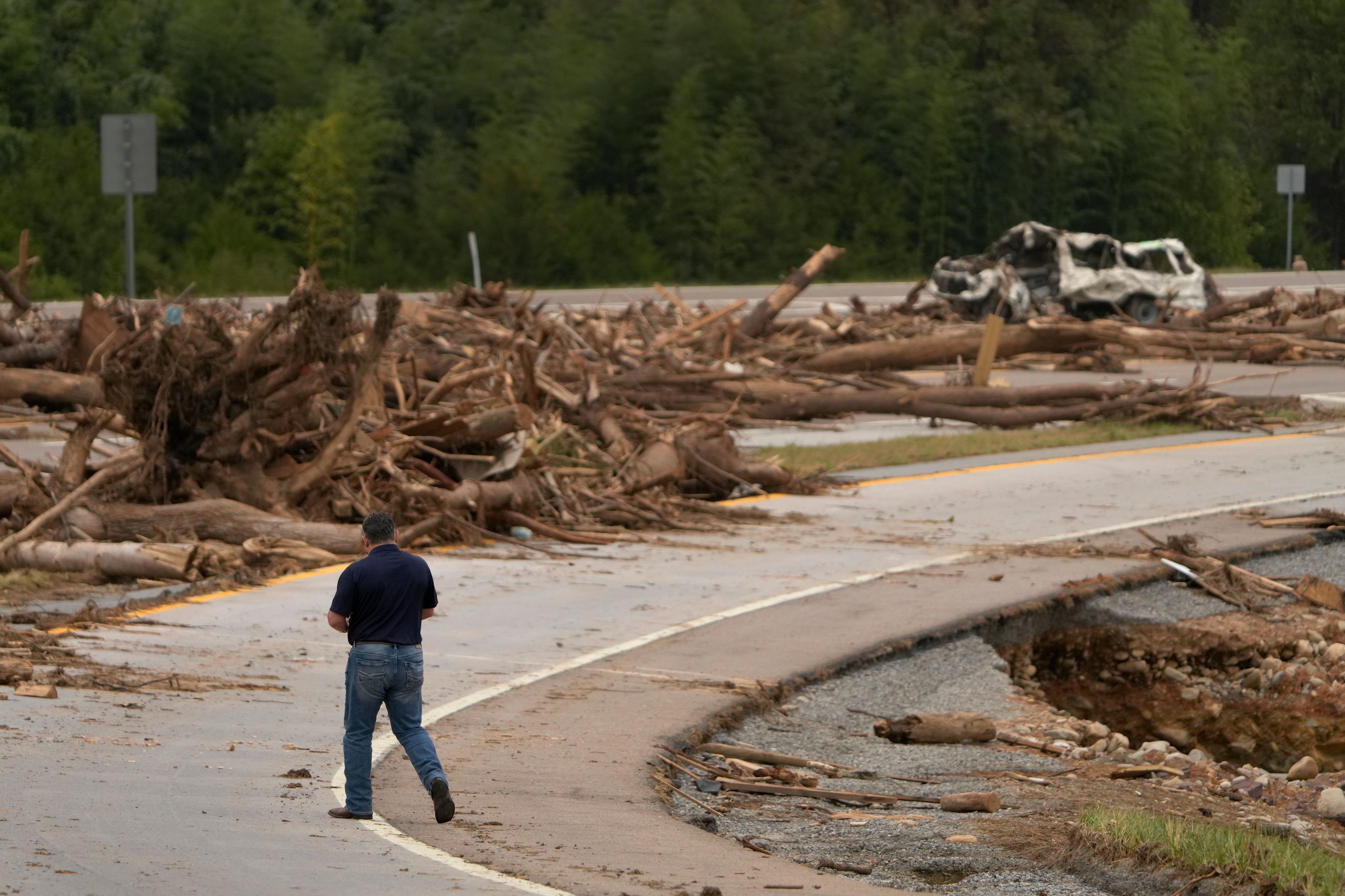 A person walks on Interstate 26 as debris covers the roadway in the aftermath of Hurricane Helene, Friday, Oct. 4, 2024, in Erwin, Tenn. (AP Photo/Jeff Roberson)