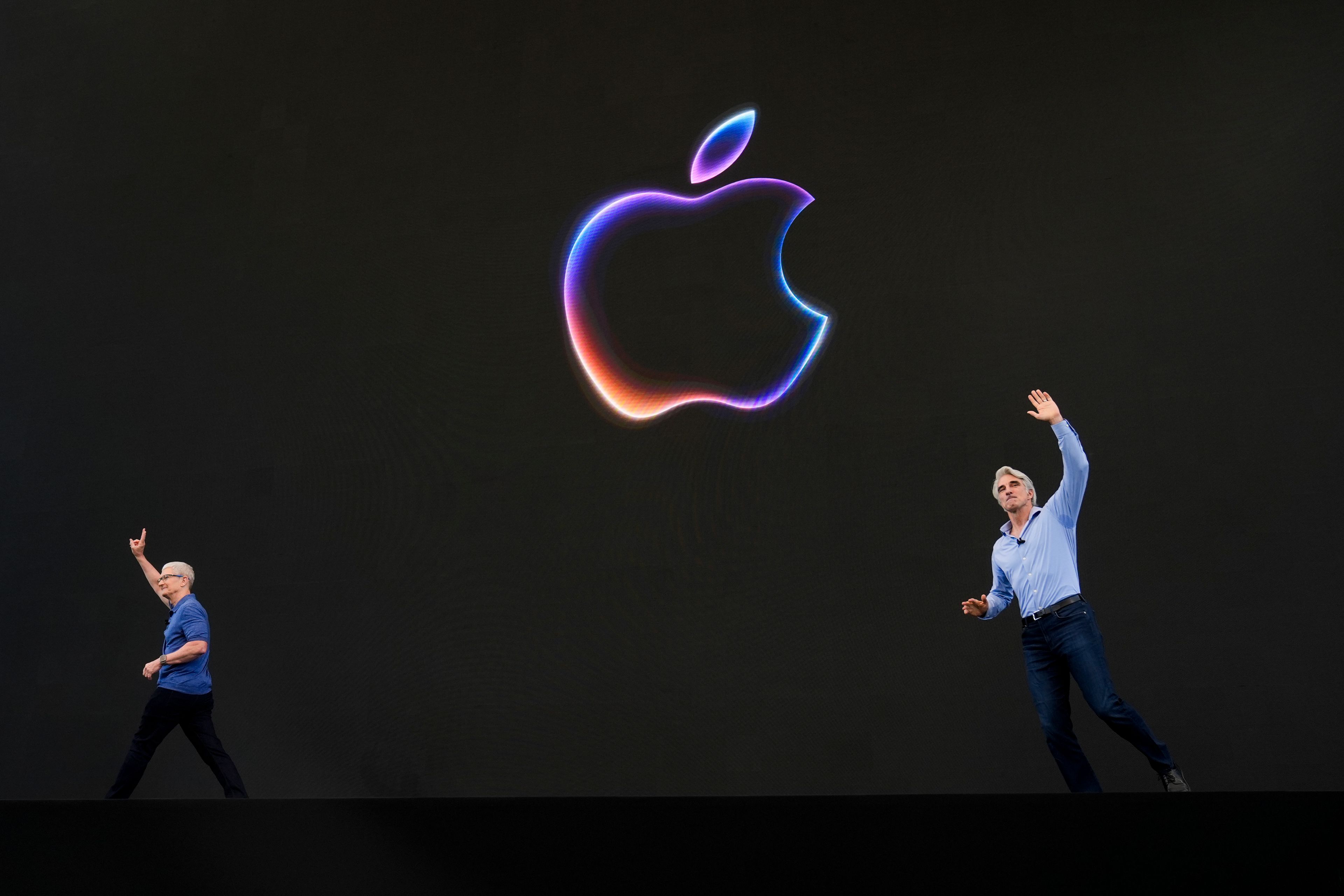 Apple CEO Tim Cook, left, exits the stage as Craig Federighi, senior vice president of software engineering, takes over during an announcement of new products at the Apple campus in Cupertino, Calif., on Monday, June 10, 2024.