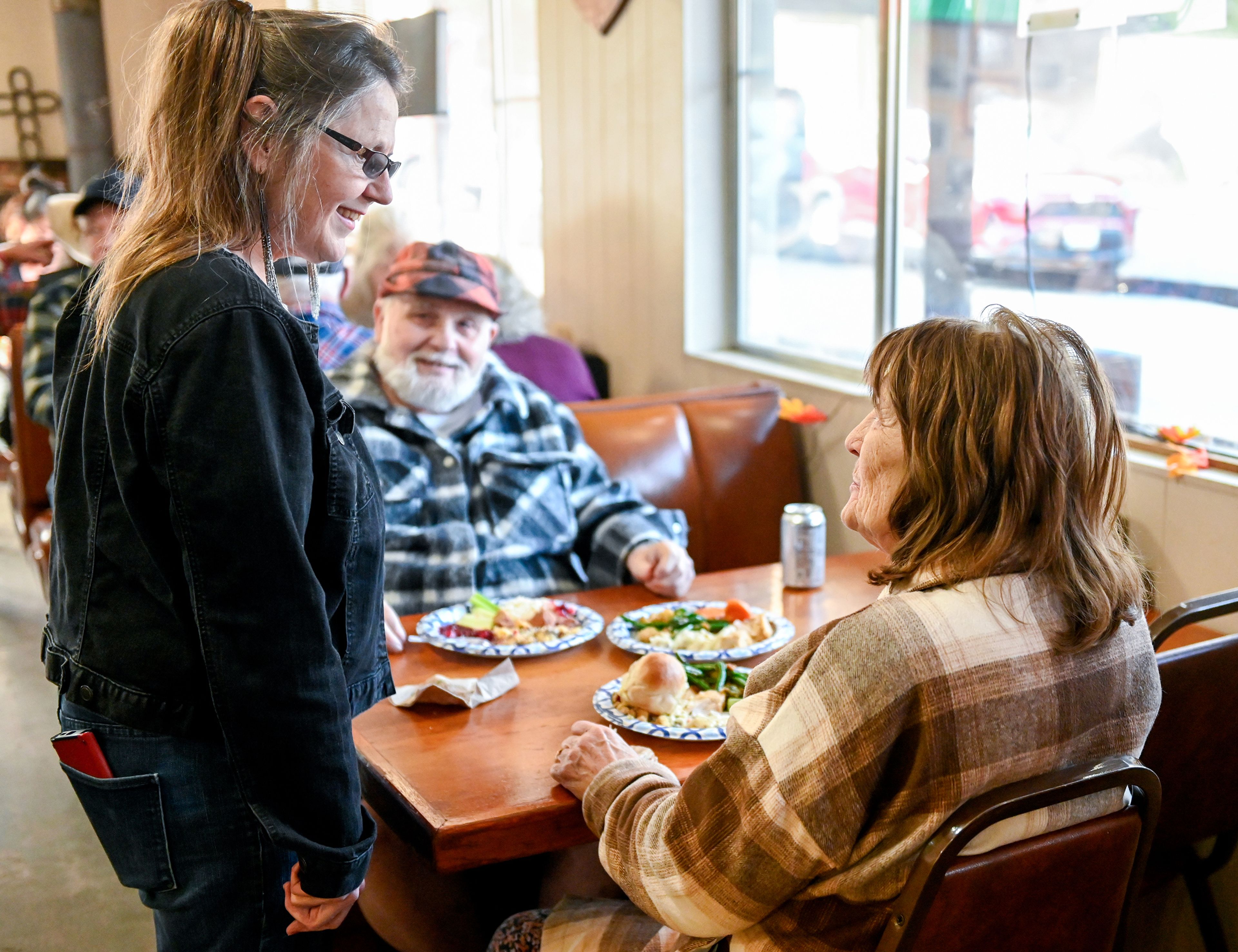 Waha Grill co-owner Wendy Hayward, left, stops by a booth to chat with long-time Waha locals Delivin Watkins, center, and Julie Watkins Thursday during the restaurant’s annual free Thanksgiving meal on the outskirts of Lewiston.