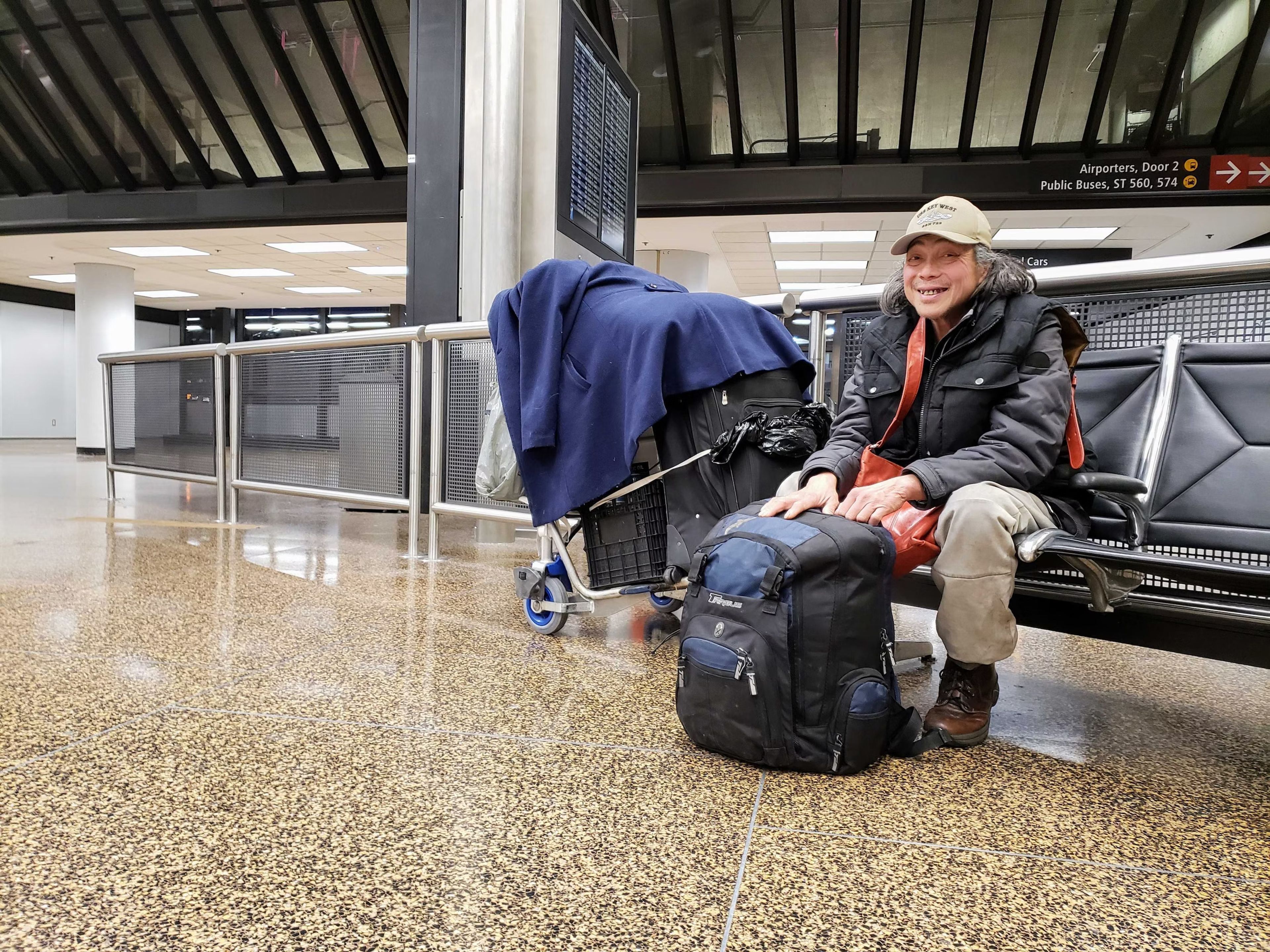 De Chung sits with his bags and belongings near a luggage carousel at SeaTac Airport on Tuesday, January 3, 2023. Credit: KUOW Photo/ Casey Martin