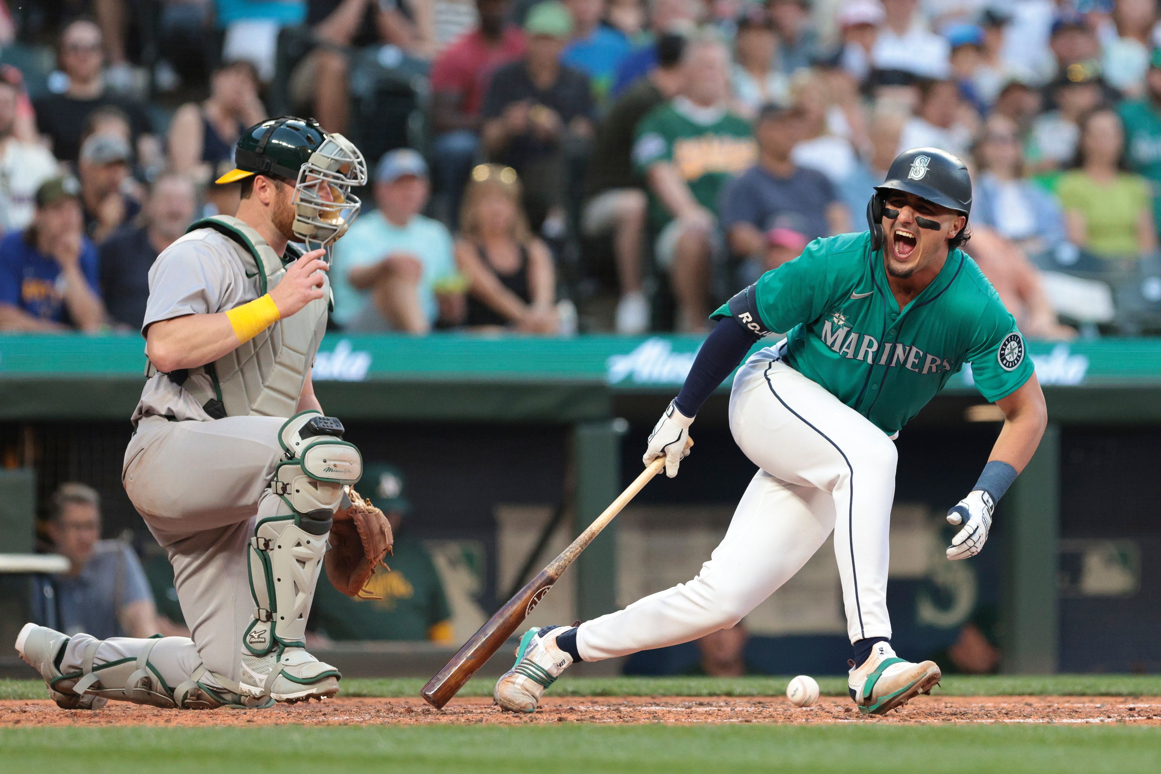 The Mariners' Josh Rojas reacts after fouling a ball off next to Athletics catcher Kyle McCann during the sixth inning of a game Saturday, May 11, 2024, in Seattle.