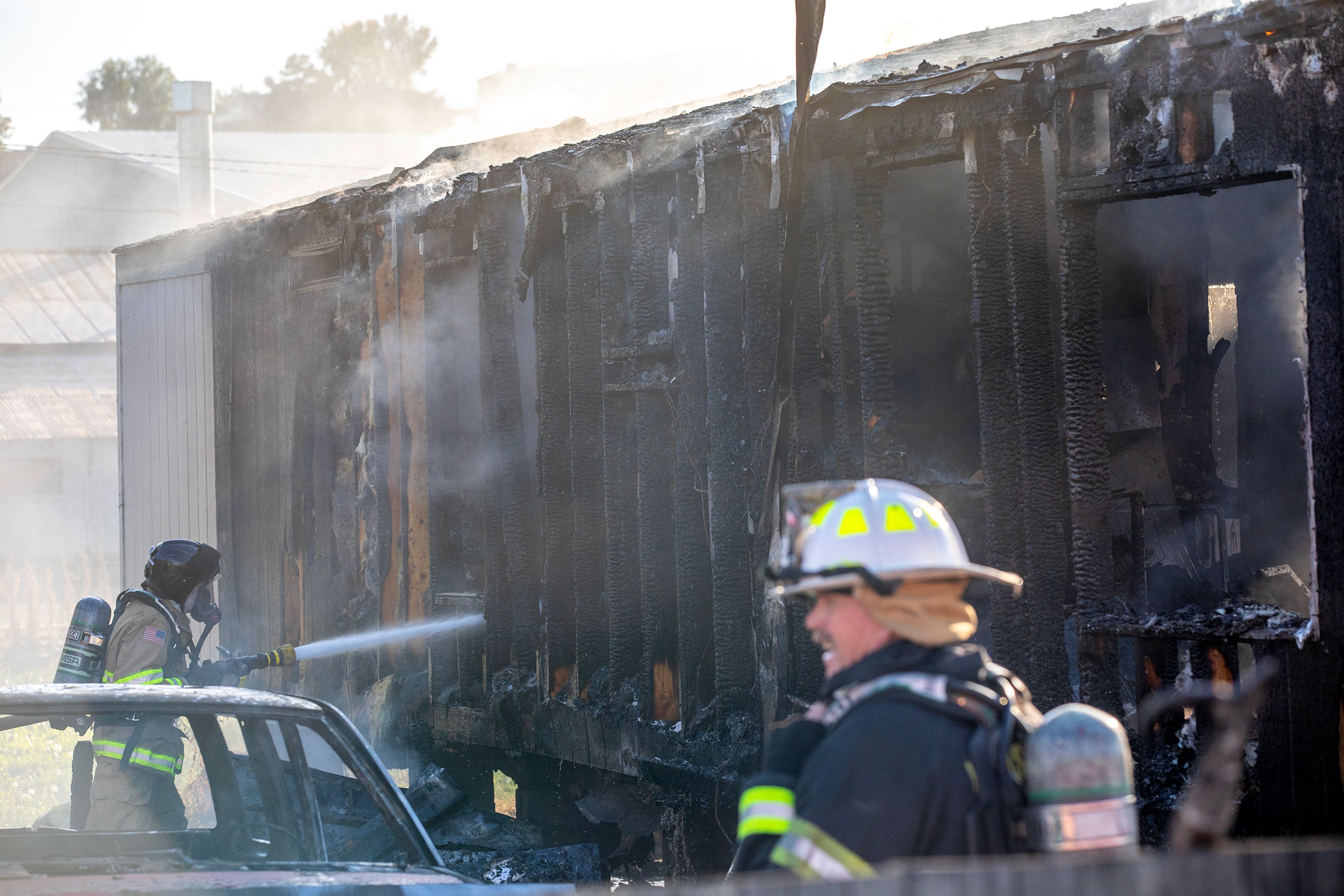 A firefighter sprays down a structure fire at a mobile home Thursday off 13th Street in Clarkston.