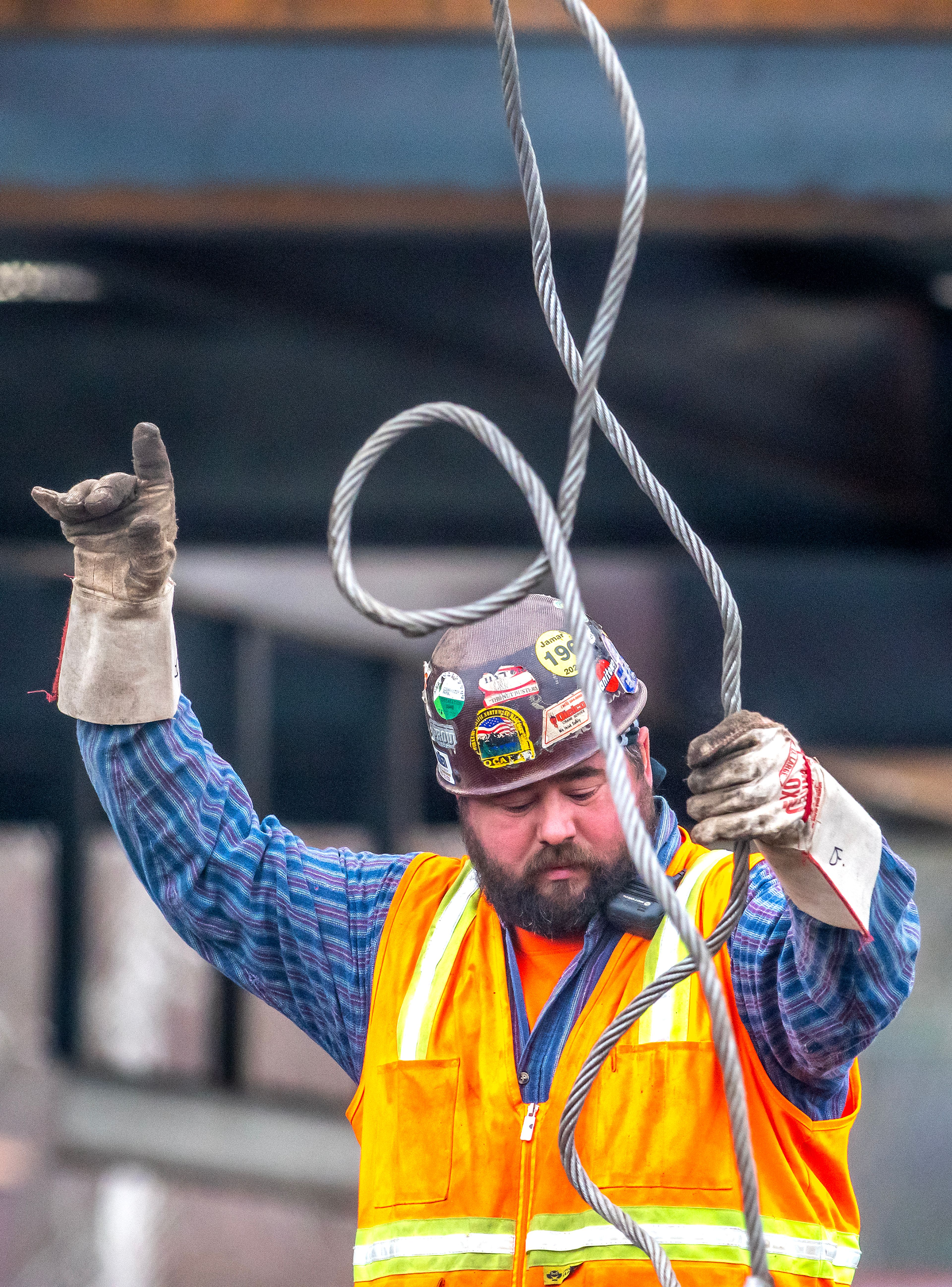 A worker directs a crane as it moves large beams of metal around Tuesday in Lewiston.