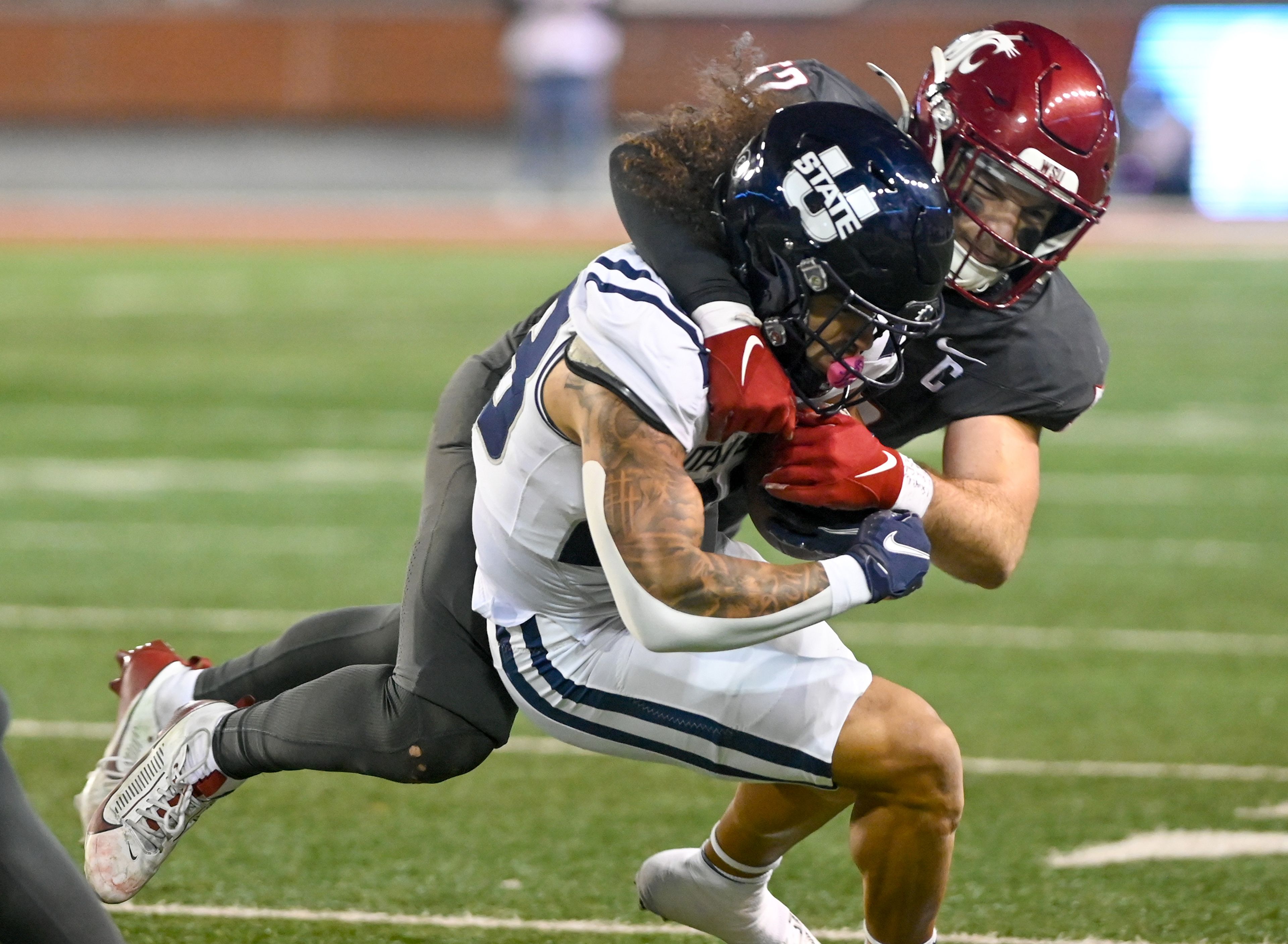 Washington State linebacker Kyle Thornton (52) tackles Utah State linebacker Tanner Williams (32) Saturday at Gesa Field in Pullman.