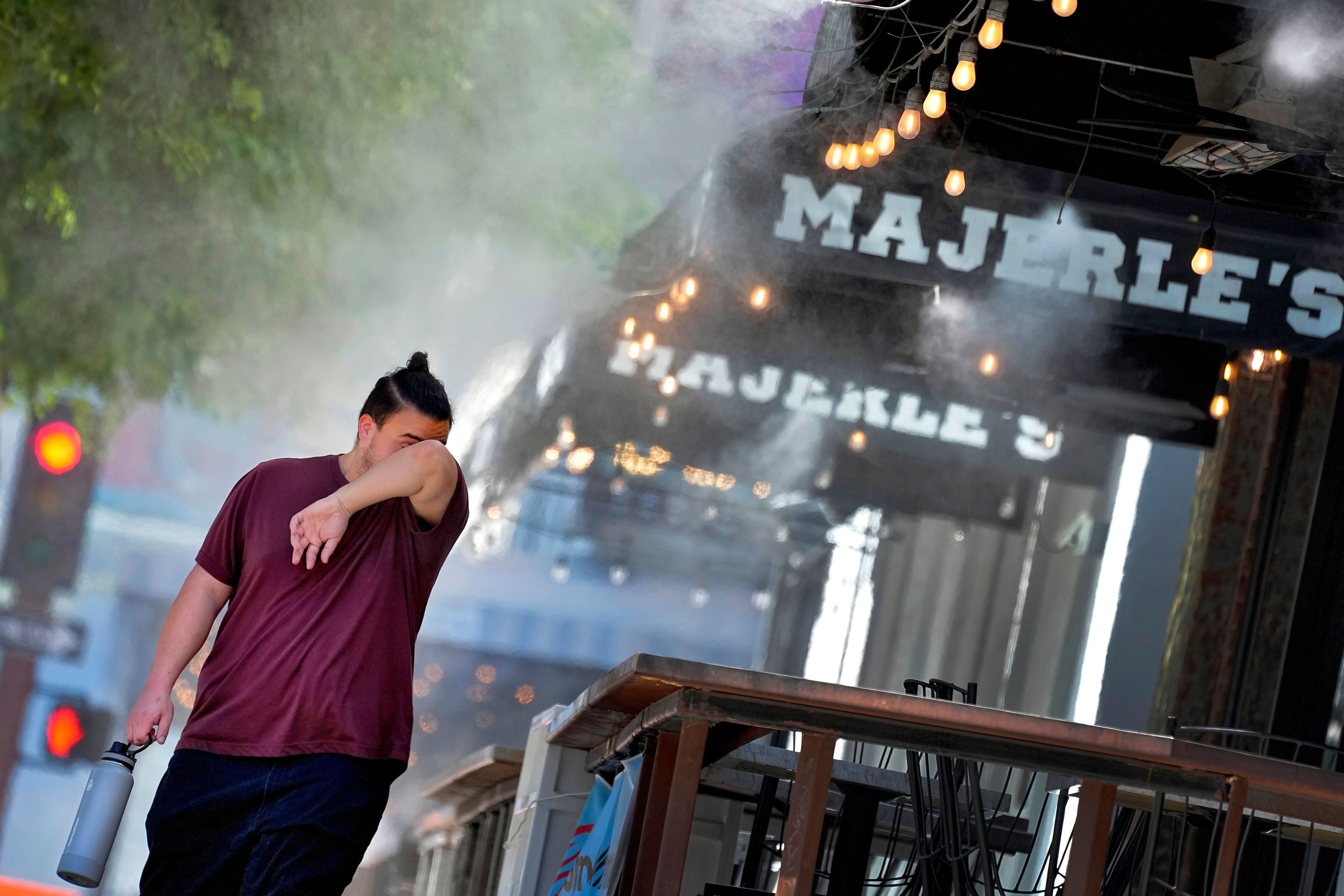 FILE - A man wipes his brow as he walks under misters, on July 13, 2023, in downtown Phoenix. The death certificates of more than 2,300 people who died in the United States last summer mention the effects of excessive heat, the highest number in 45 years of records, according to an Associated Press analysis of Centers for Disease Control and Prevention data. With May already breaking heat records, 2024 could be even deadlier. (AP Photo/Matt York, File)