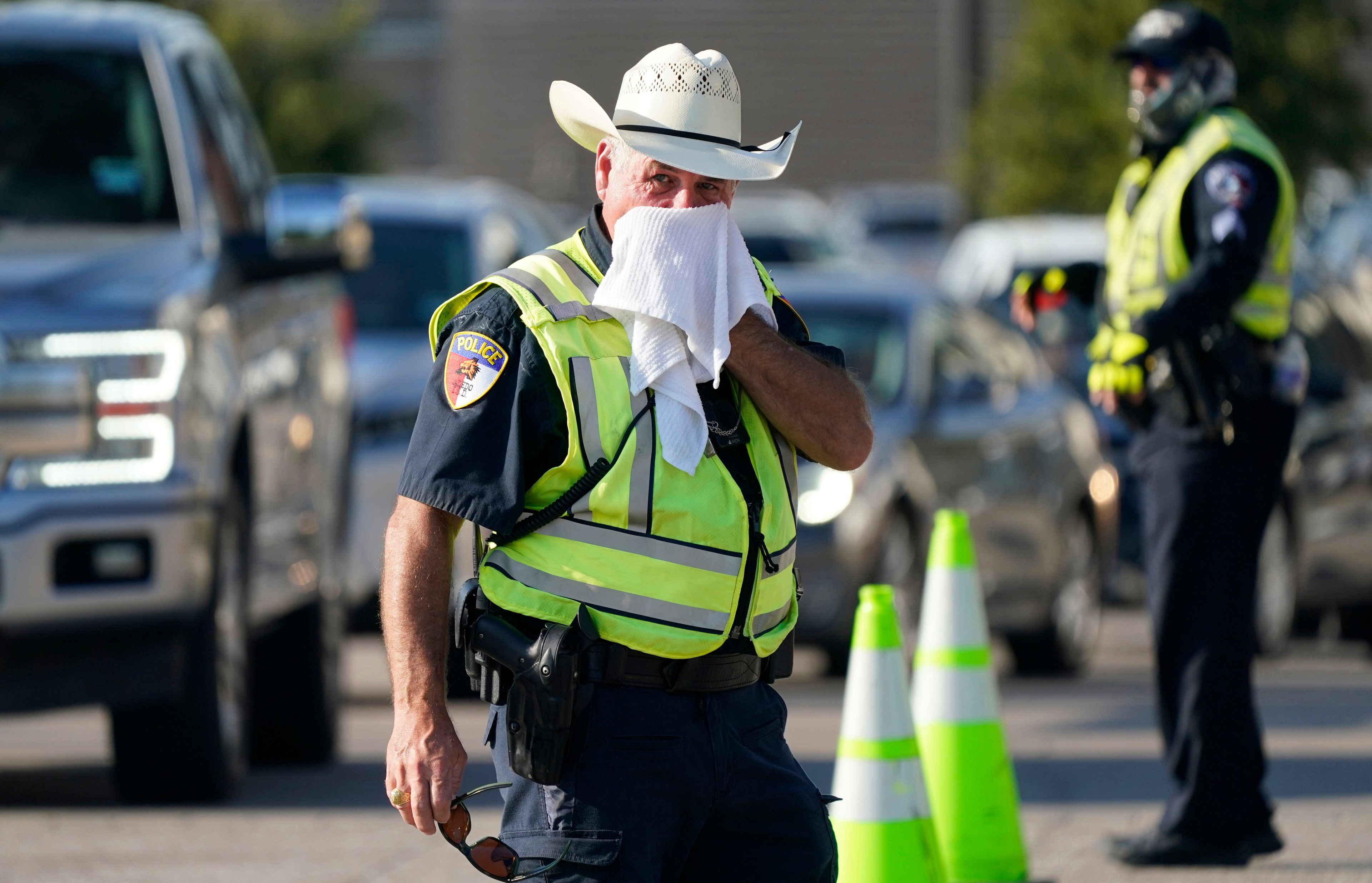 FILE - Police officer James Rhodes uses a wet towel to cool off as he directs traffic after a sporting event in Arlington, Texas, on Aug. 19, 2023. The death certificates of more than 2,300 people who died in the United States last summer mention the effects of excessive heat, the highest number in 45 years of records, according to an Associated Press analysis of Centers for Disease Control and Prevention data. With May already breaking heat records, 2024 could be even deadlier. (AP Photo/LM Otero, File)