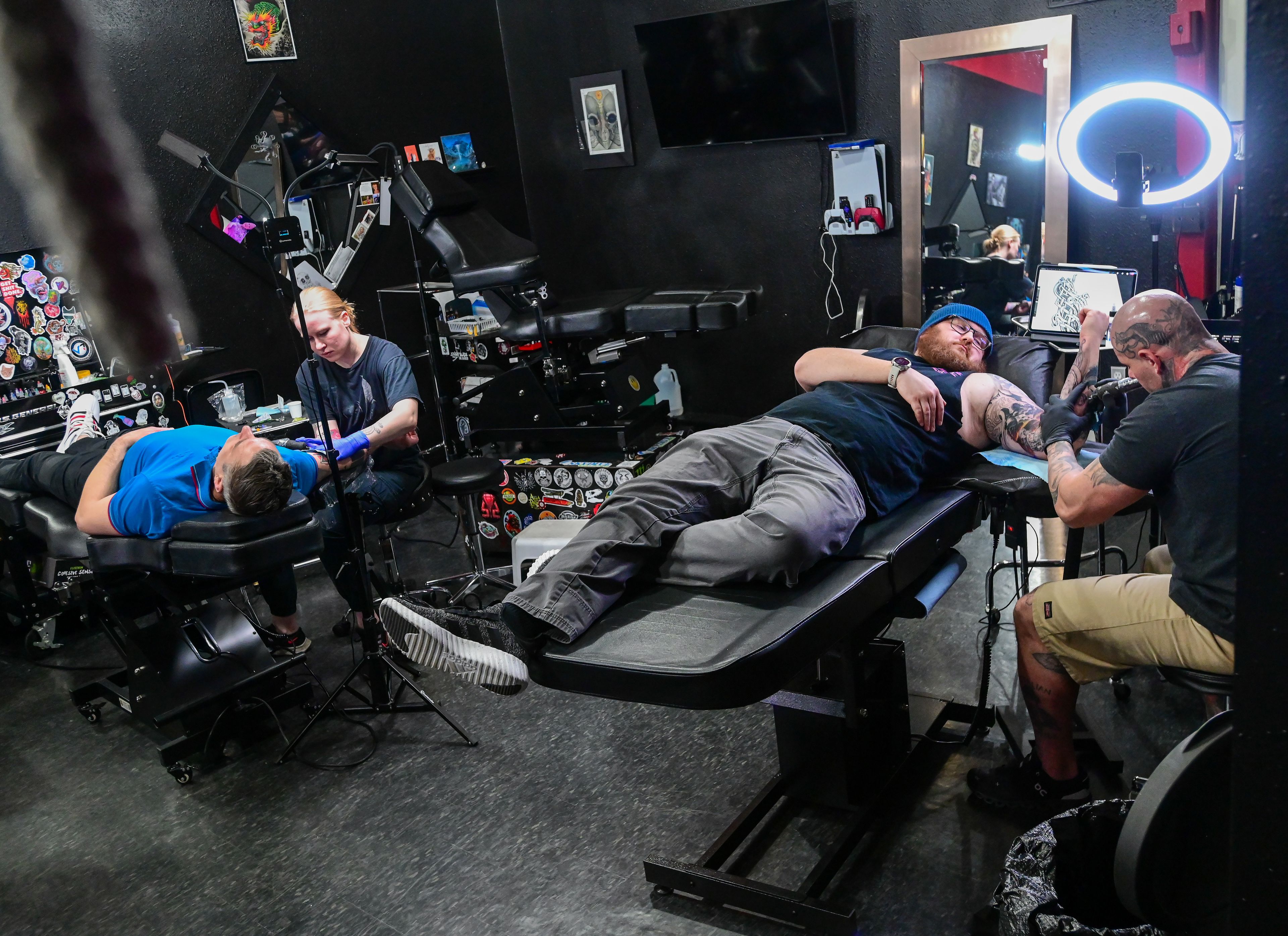 Lee Fleming, left, of Pullman, and Jake McLean, of Lewiston, lay in tattoo chairs as Blood Diamond Ink tattoo artist Sarah Bailey, center, and co-owner Chris Peltier, right, work on their body art on Friday, Feb 23.