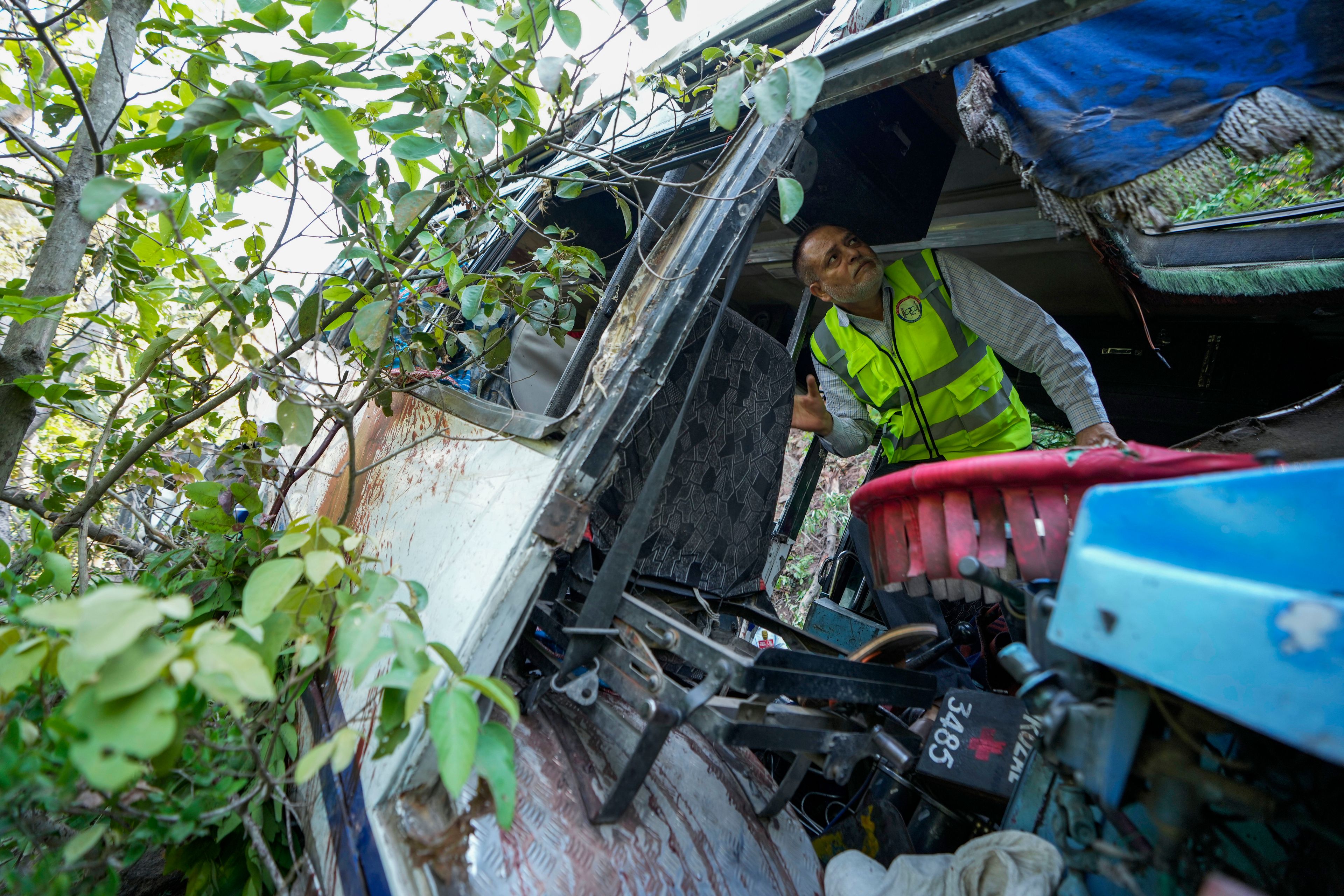 A forensic official inspects a bus that fell into a deep gorge on Sunday after being fired at by suspected militants in Reasi district, Jammu and Kashmir, Monday, June 10, 2024. The bus was carrying pilgrims to the base camp of the famed Hindu temple Mata Vaishno Devi when it came under attack killing at least nine people.