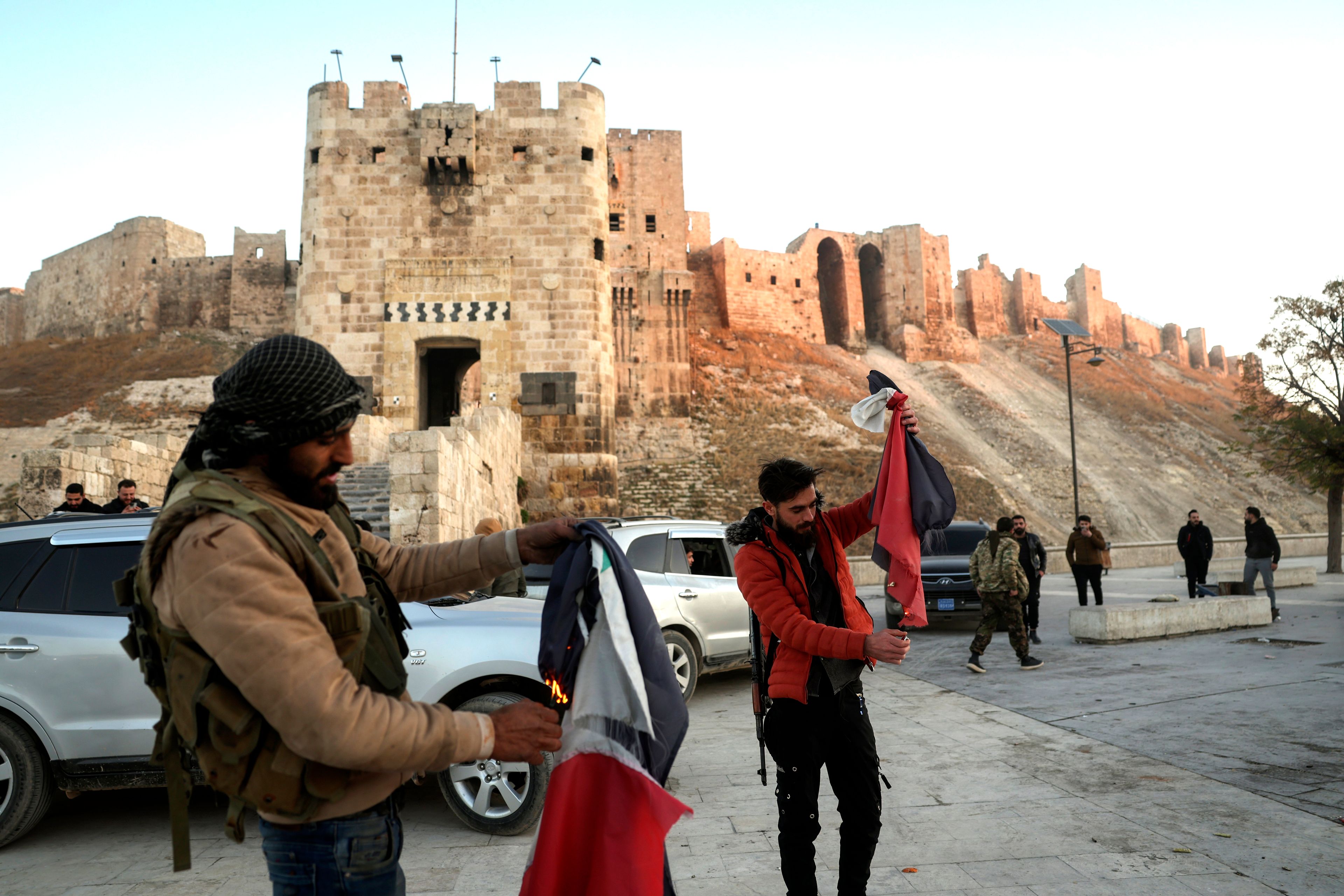 Syrian opposition fighters burn government Syrian flags for the cameras next to Aleppo's old city, Saturday Nov. 30, 2024. (AP Photo/Ghaith Alsayed)