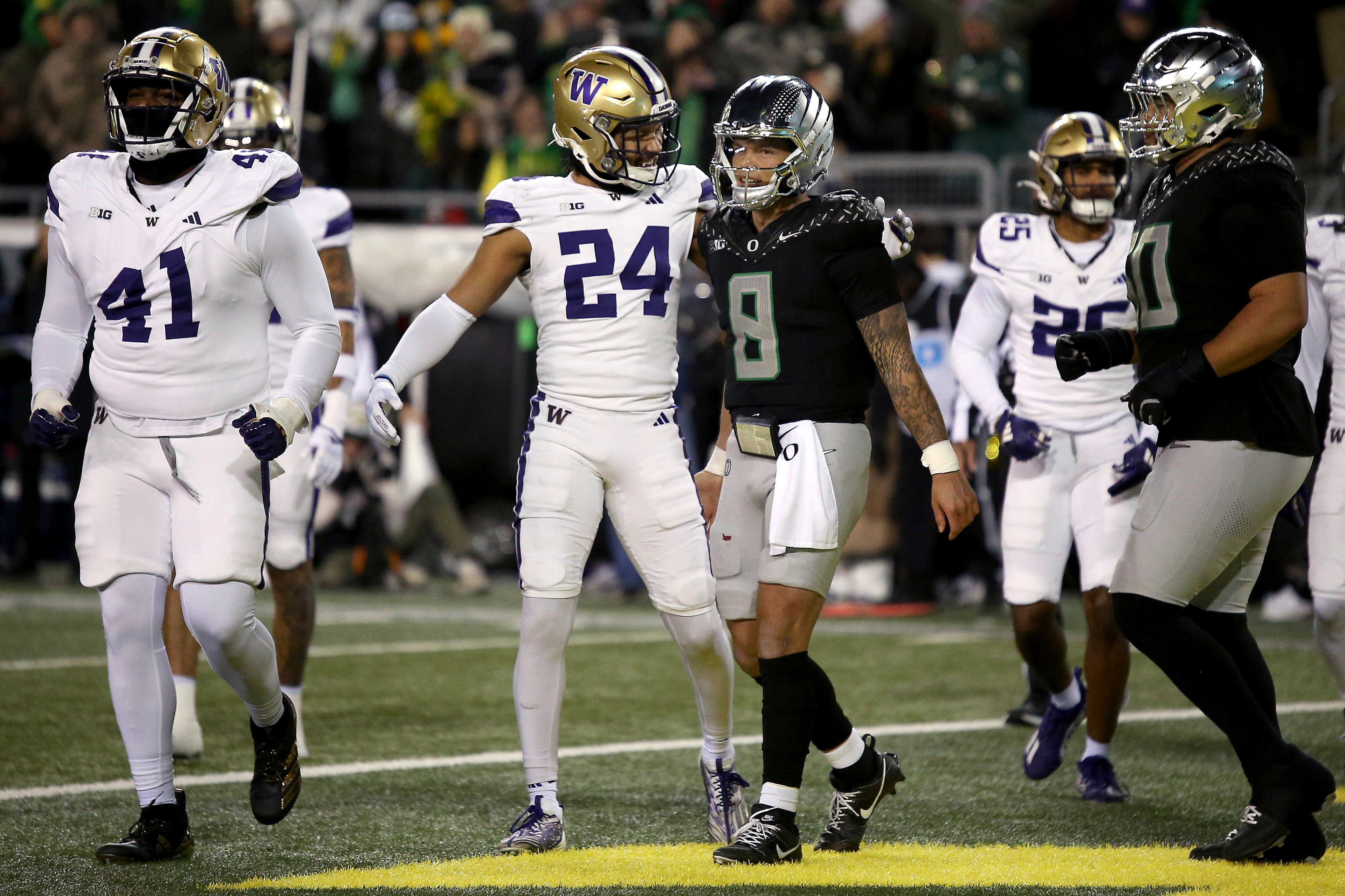 Washington safety Makell Esteen (24) and Oregon quarterback Dillon Gabriel (8) speak after an Oregon touchdown during an NCAA college football game, Saturday, Nov. 30, 2024, in Eugene, Ore. (AP Photo/Lydia Ely)