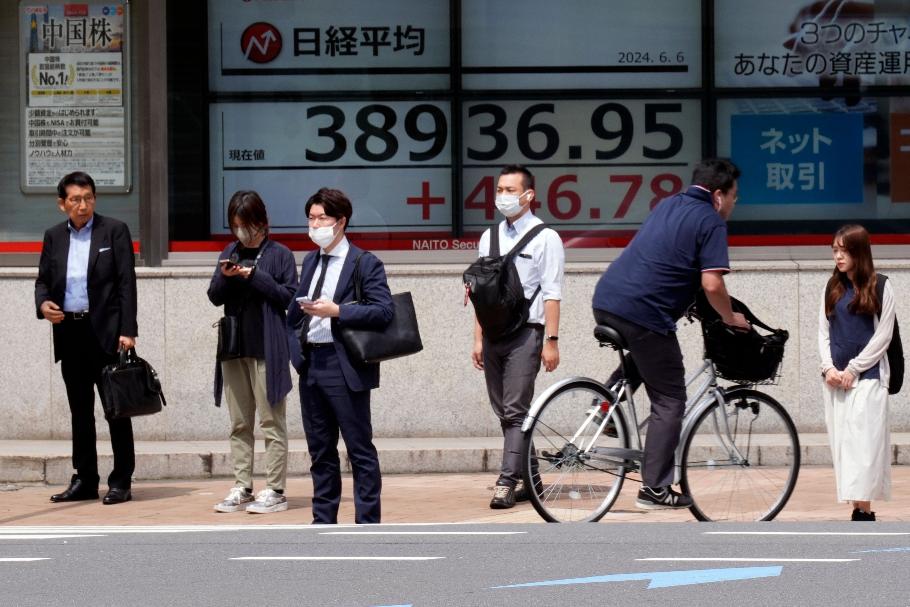 People stand in front of an electronic stock board showing Japan's Nikkei 225 index at a securities firm Thursday, June 6, 2024, in Tokyo.