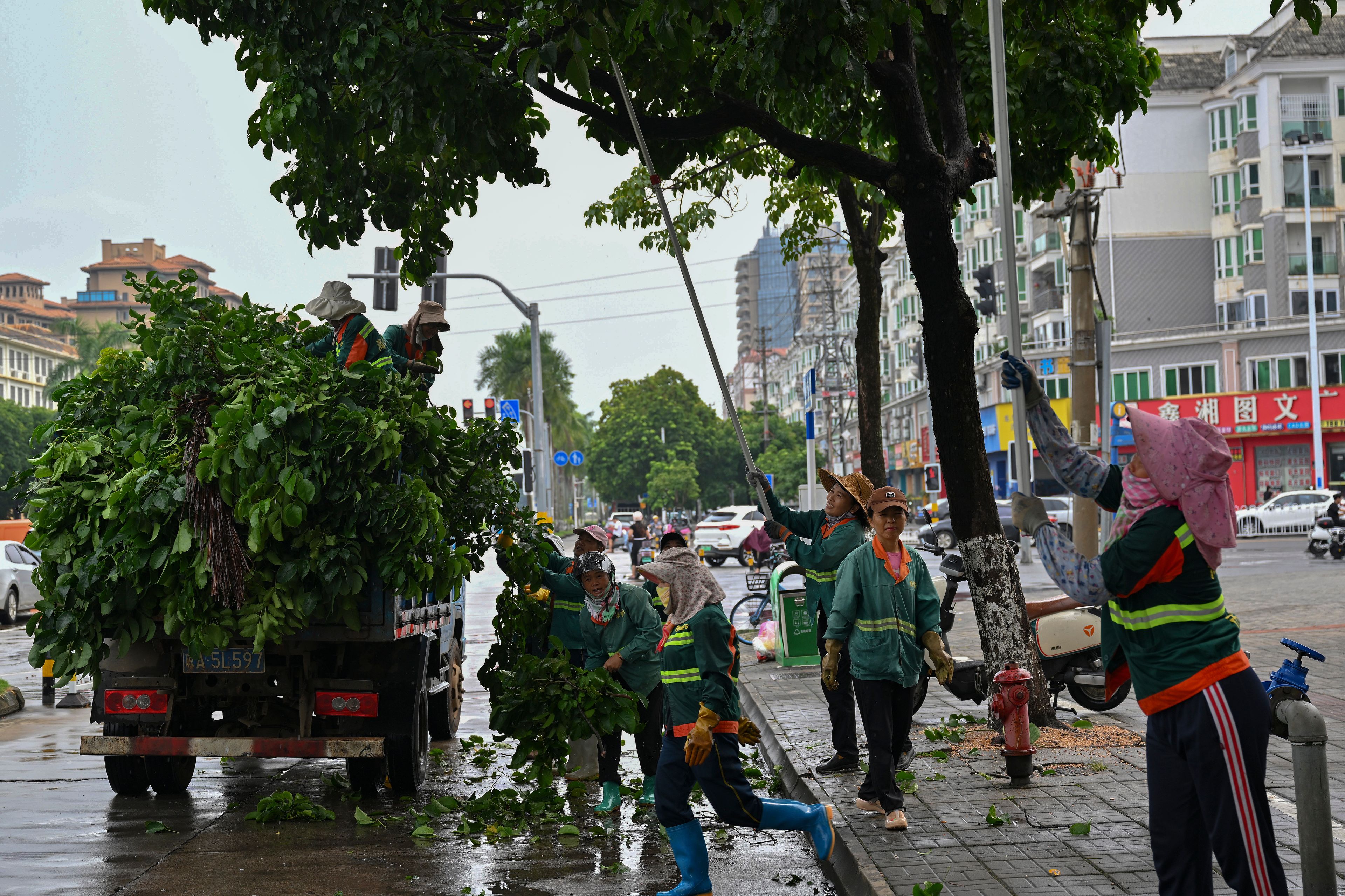 In this image released by Xinhua News Agency, workers cut redundant branches off of trees along a street ahead of the landfall of typhoon Yagi in Haikou, south China's Hainan Province, Thursday, Sept. 5, 2024.